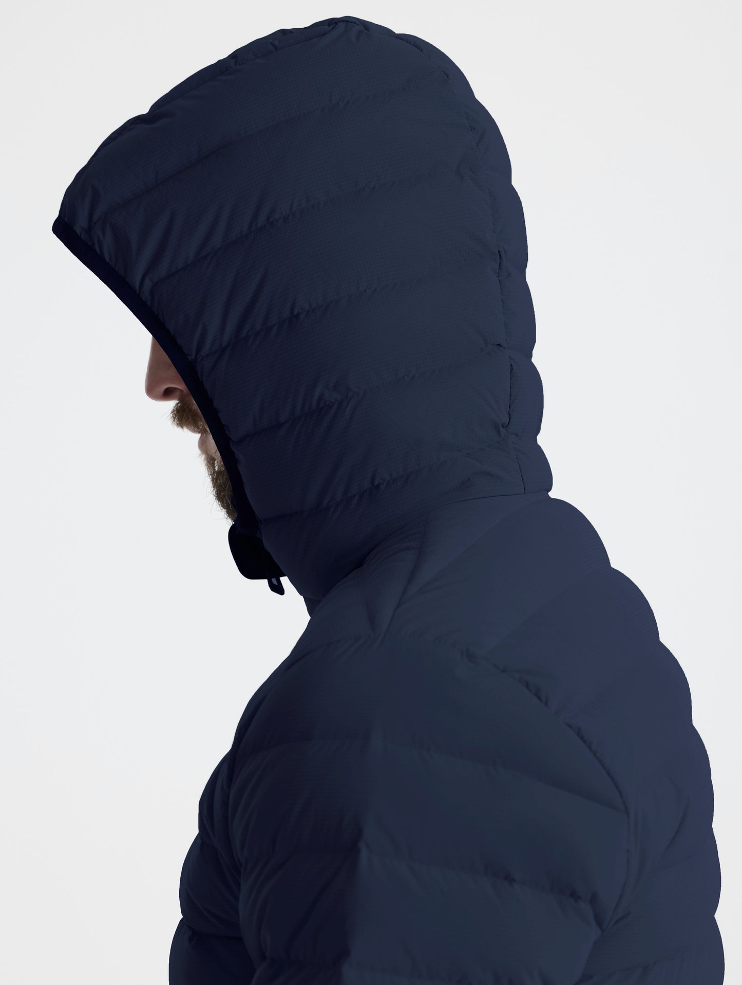 Closeup left profile view of man wearing hood of Launch Full-Zip Hooded Jacket in Total Eclipse dark blue from AETHER Apparel.