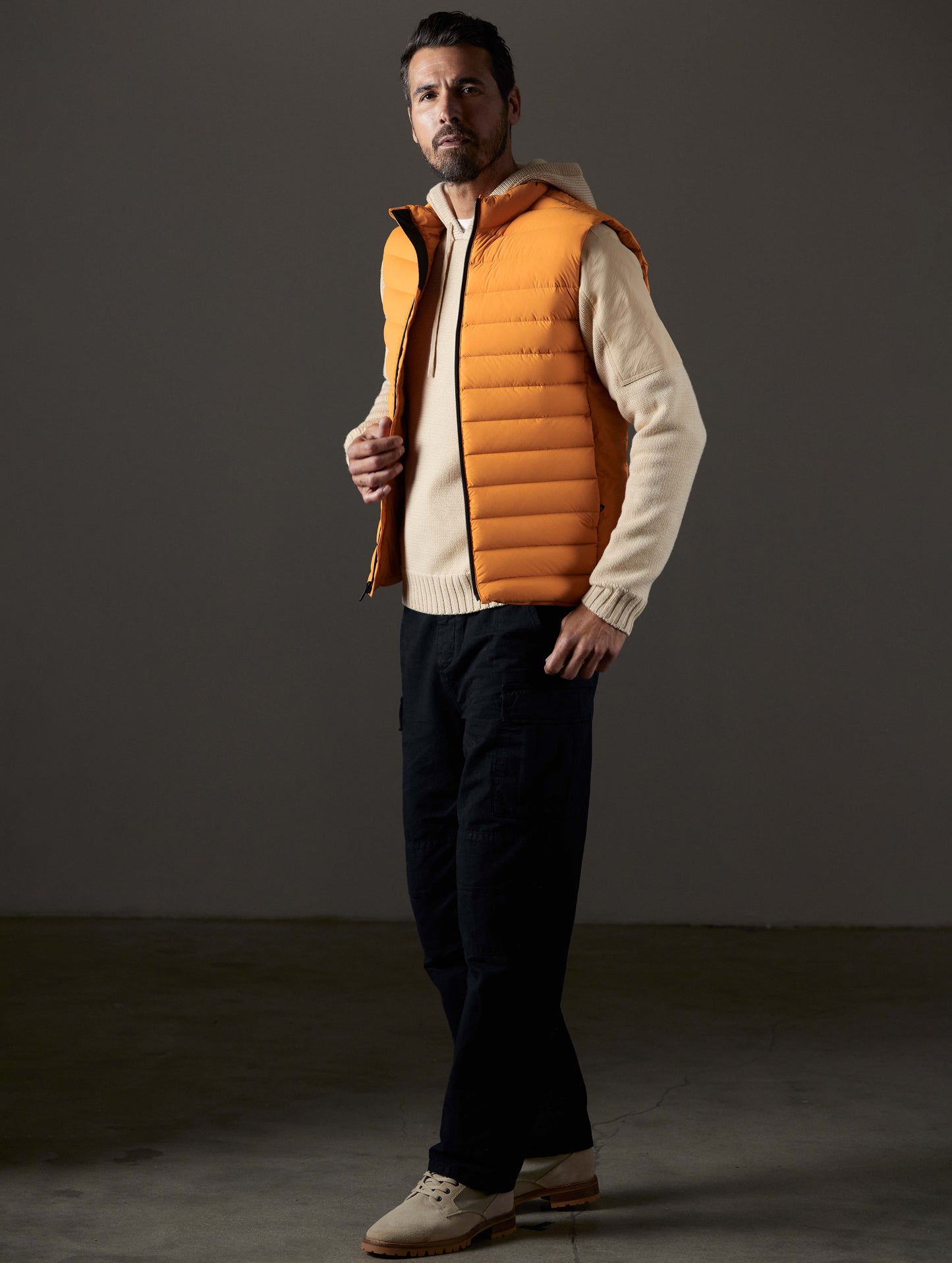 Front 3/4 full-body view of man wearing Launch Vest in Midas Orange from AETHER Apparel.