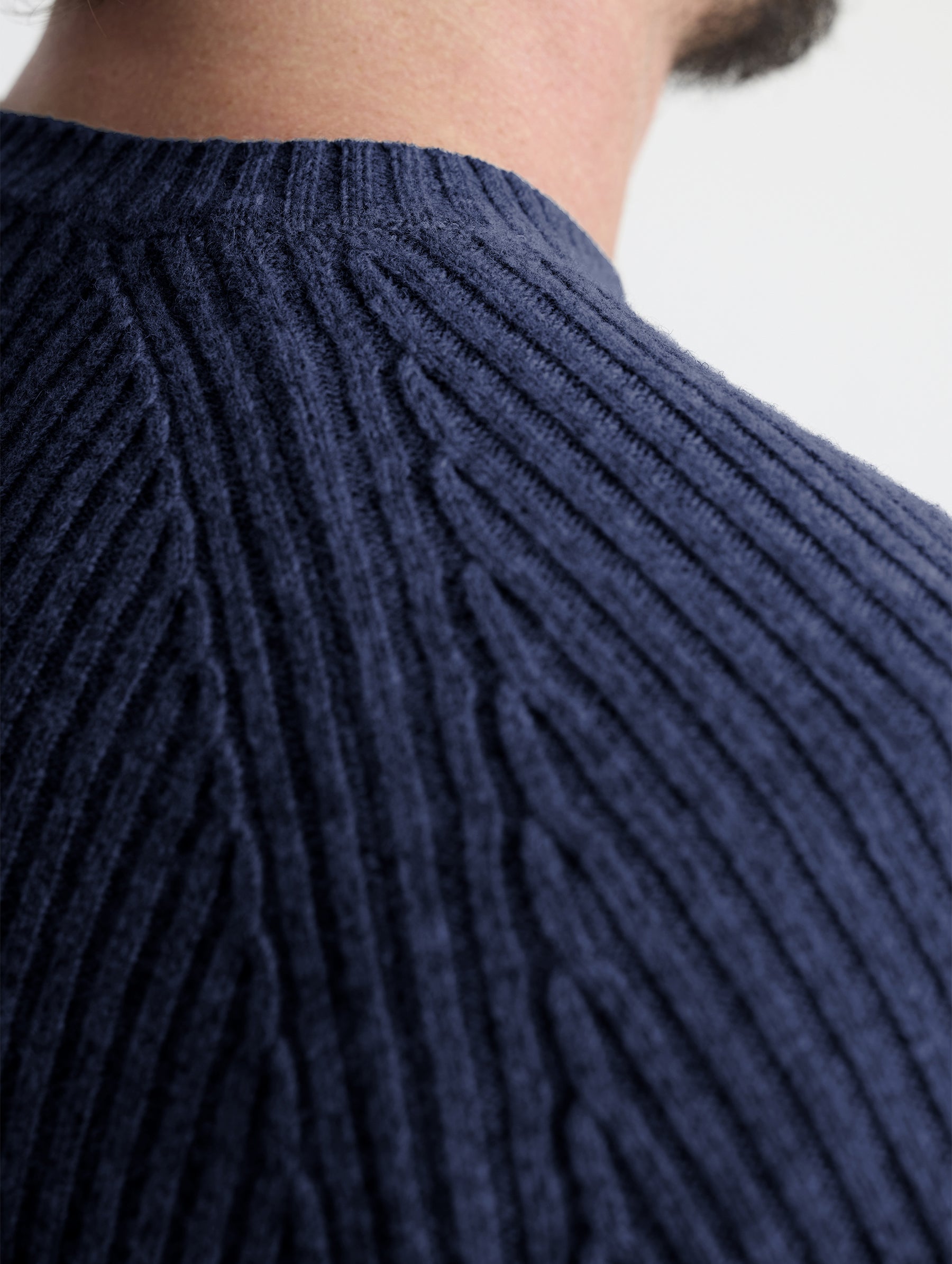 Closeup rear view of wearer's right shoulder stitch of Lyon Sweater in Total Eclipse dark blue from AETHER Apparel.
