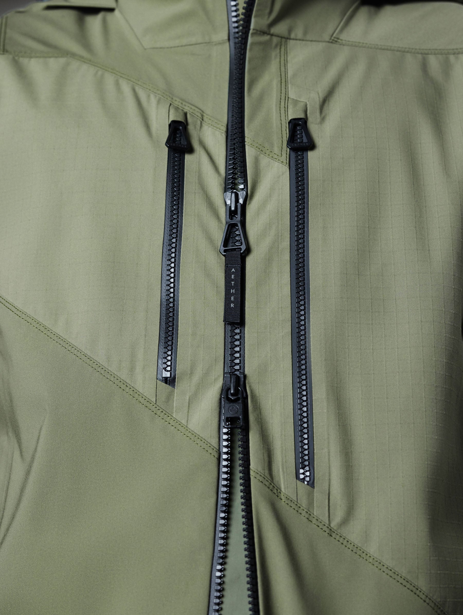 Closeup detailed view of the AquaGuard zipper-secured chest pockets and weatherproof two-way main center-front zipper of the Maverick Snow-Shell Jacket in Fern Green from AETHER Apparel.