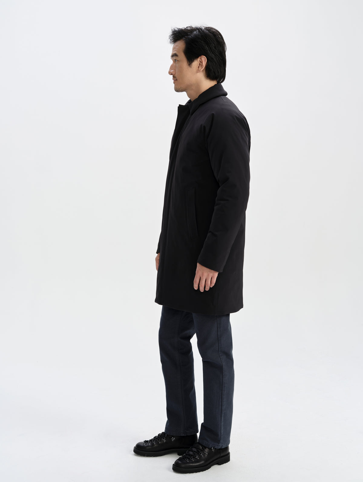 Side profile full-body view of man wearing the Maxwell Insulated Trench in Onyx Black from AETHER Apparel.