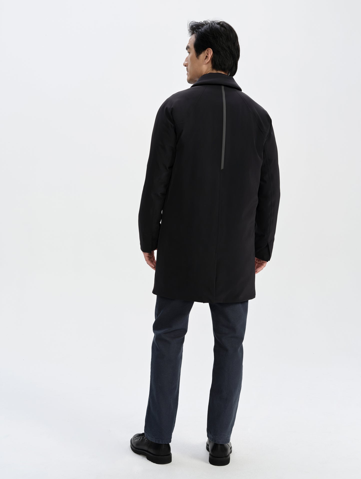 Rear full-body view of man wearing the Maxwell Insulated Trench in Onyx Black from AETHER Apparel.