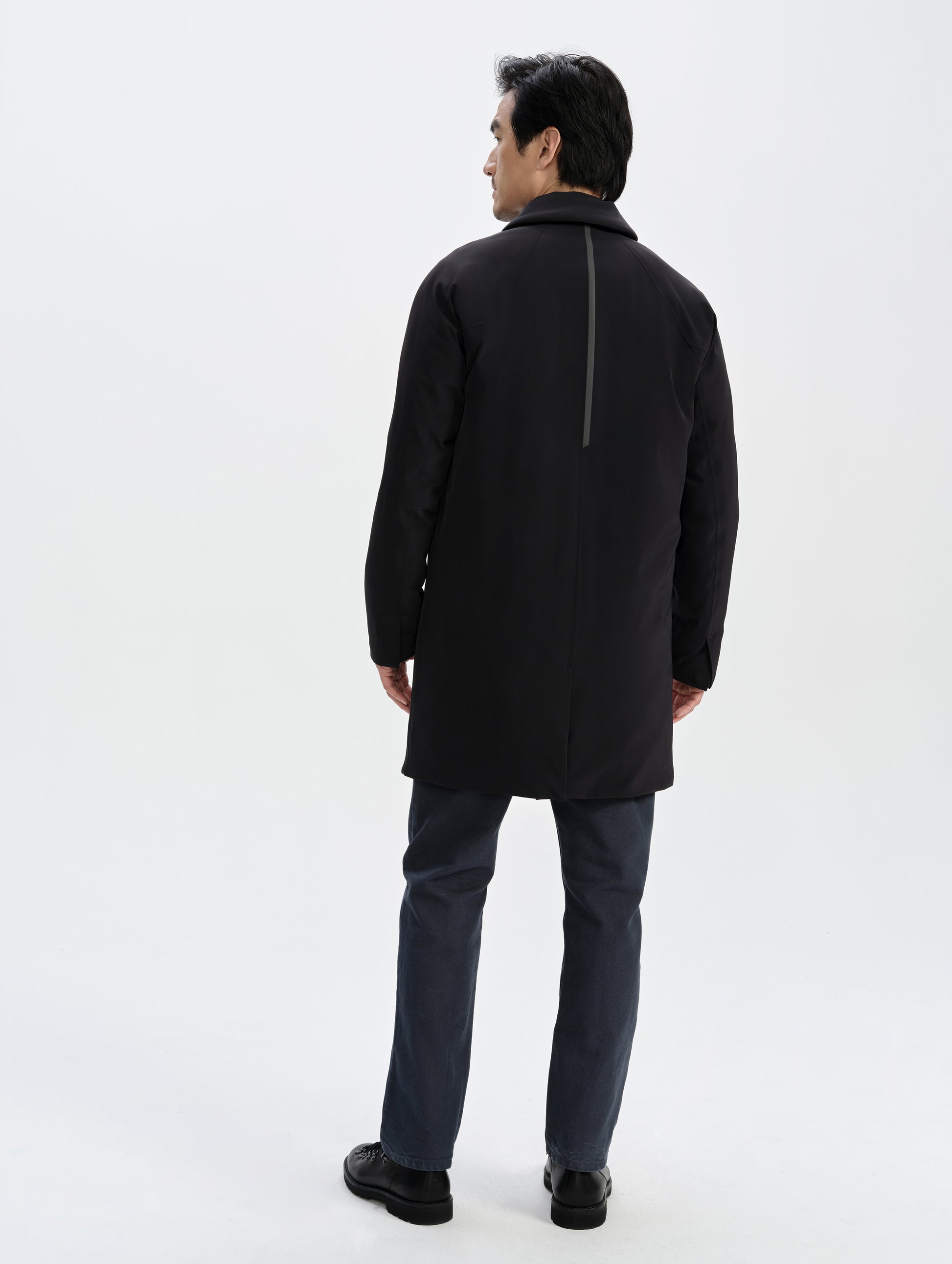 Rear full-body view of man wearing the Maxwell Insulated Trench in Onyx Black from AETHER Apparel.