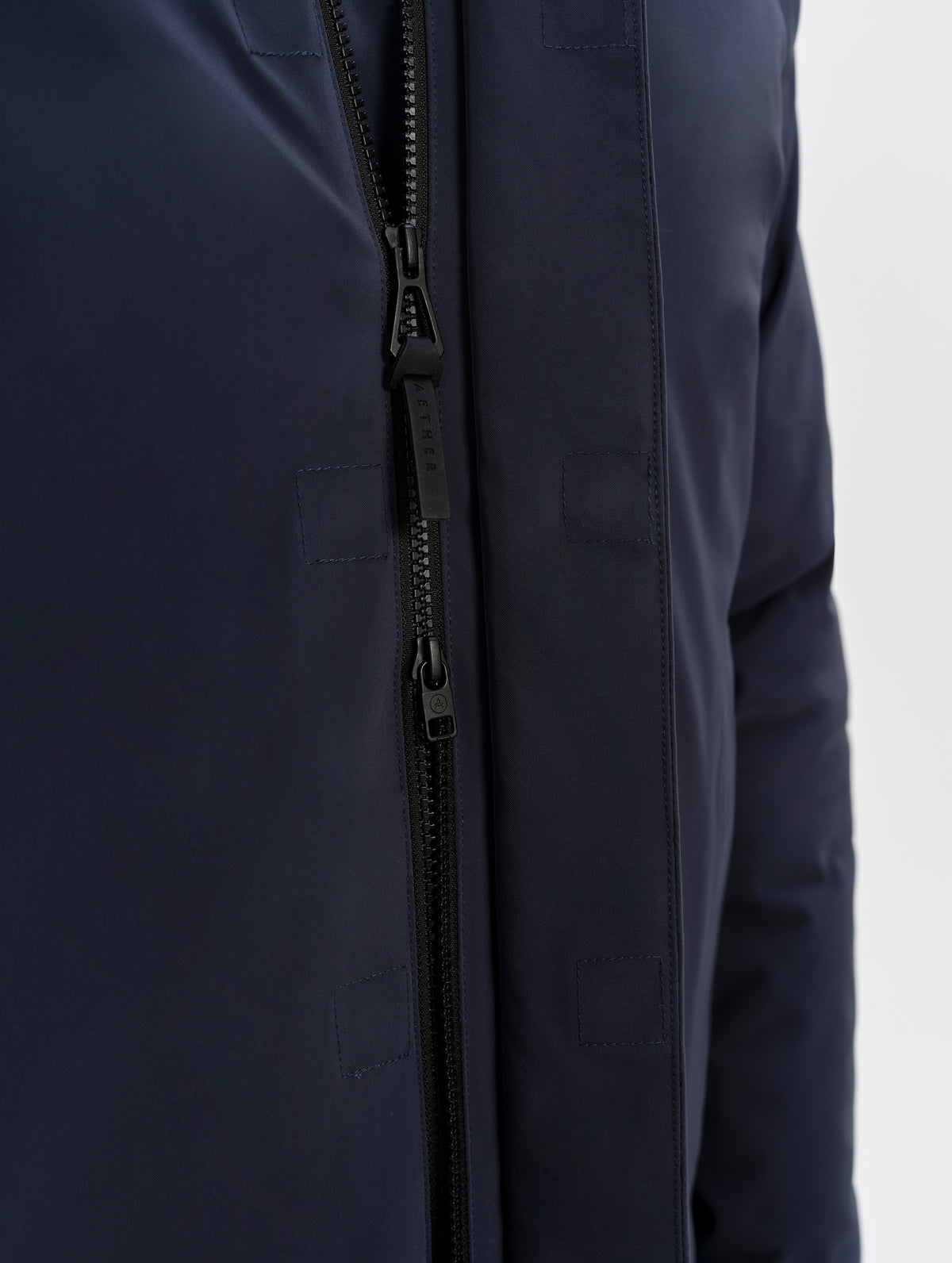 Closeup detailed view of the main center-front two-way zipper on the Maxwell Insulated Trench in Total Eclipse from AETHER Apparel.