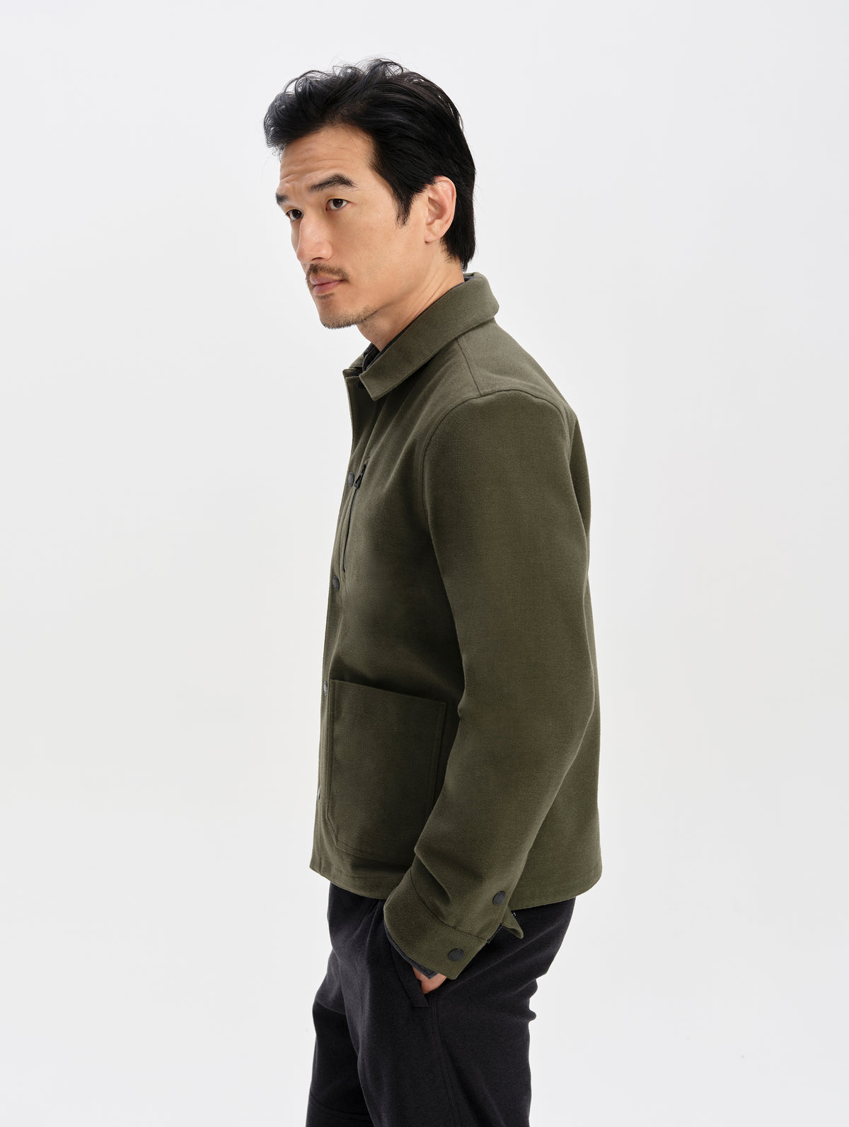 Side profile upper-body view of man wearing the Milton Chore Jacket in Forest Green from AETHER Apparel.