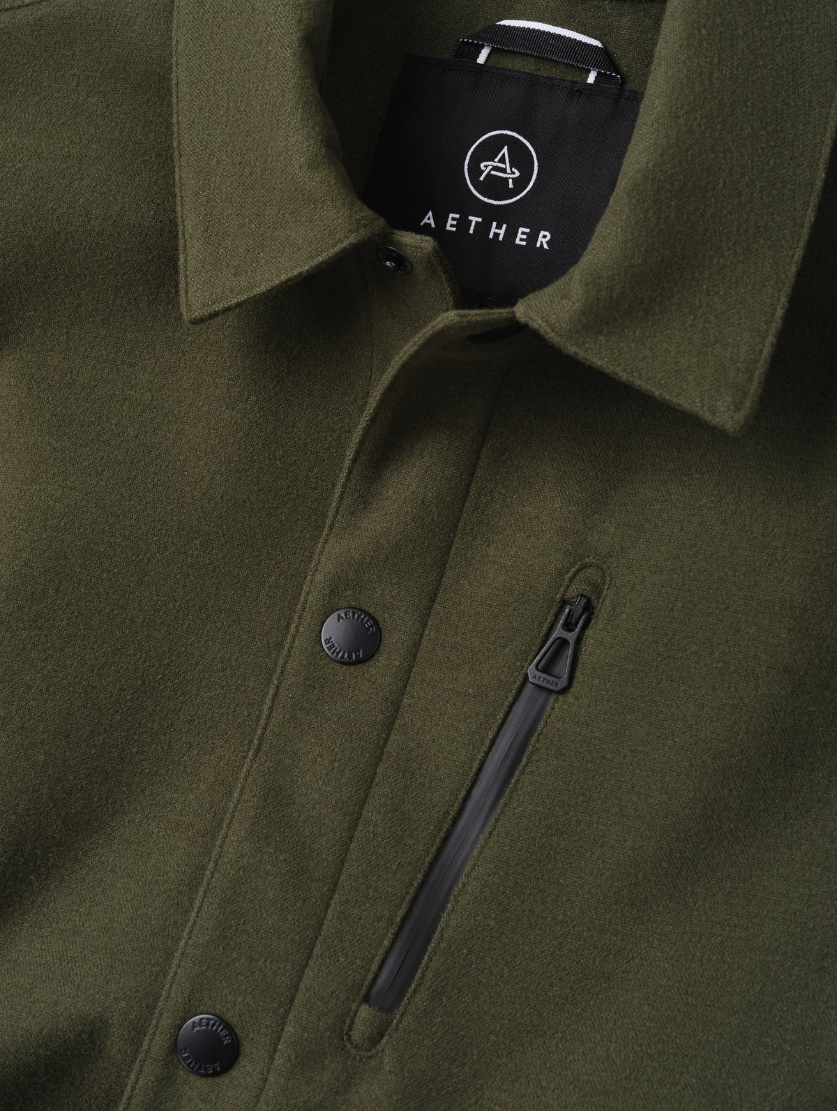 Closeup detailed view of the center-front snap closure and zipper-secured chest pocket on the Milton Chore Jacket in Forest Green from AETHER Apparel. 