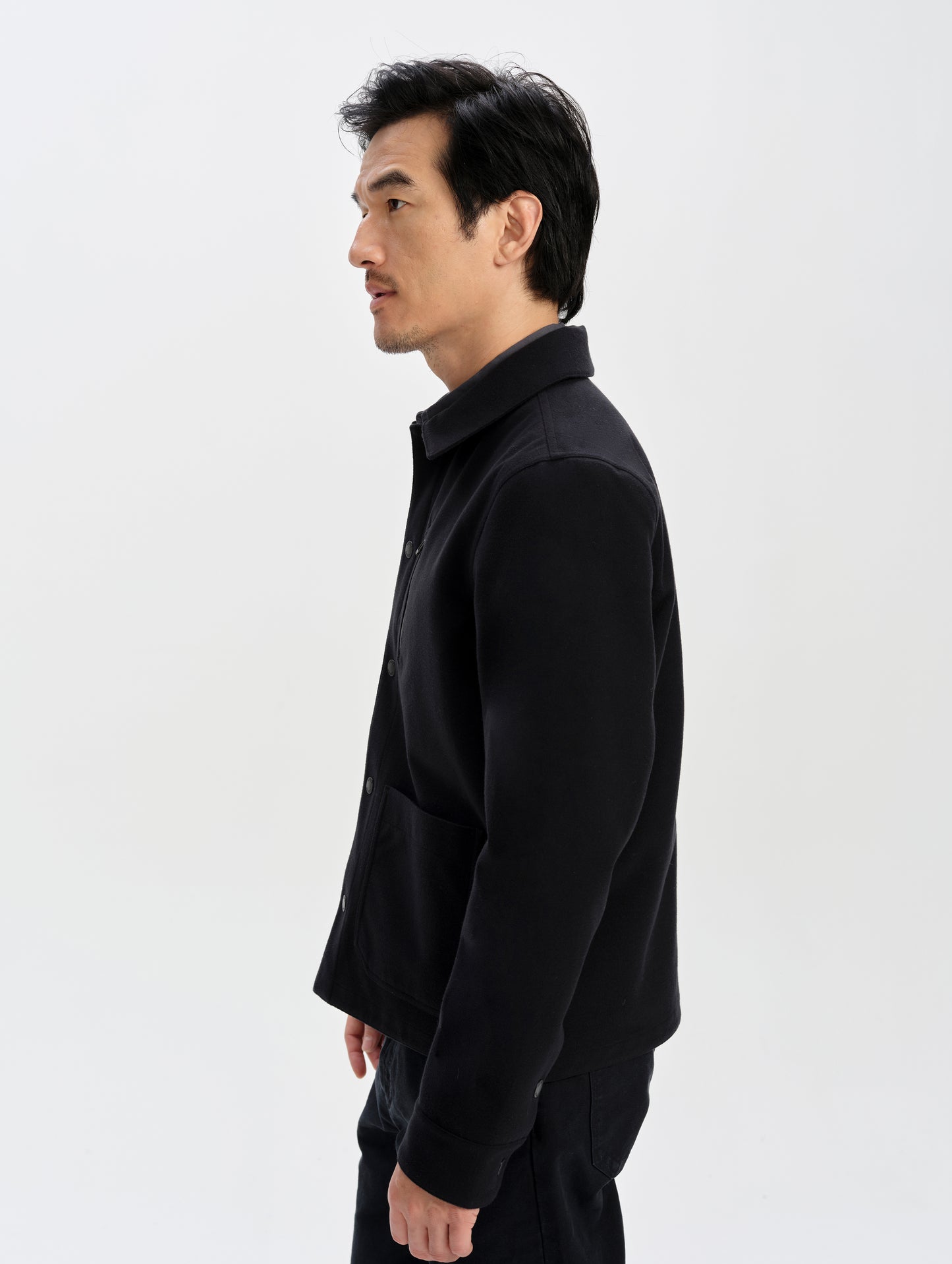 Side profile upper-body view of man wearing the Milton Chore Jacket in Onyx Black from AETHER Apparel. 