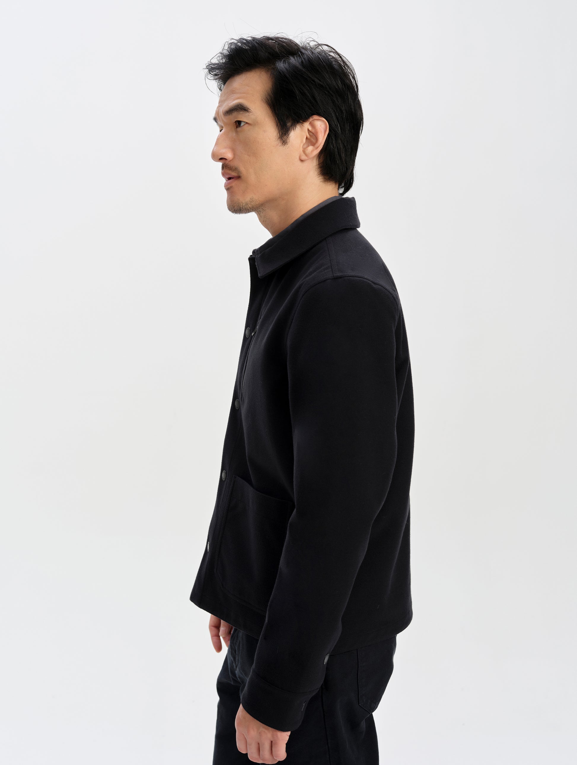 Side profile upper-body view of man wearing the Milton Chore Jacket in Onyx Black from AETHER Apparel. 