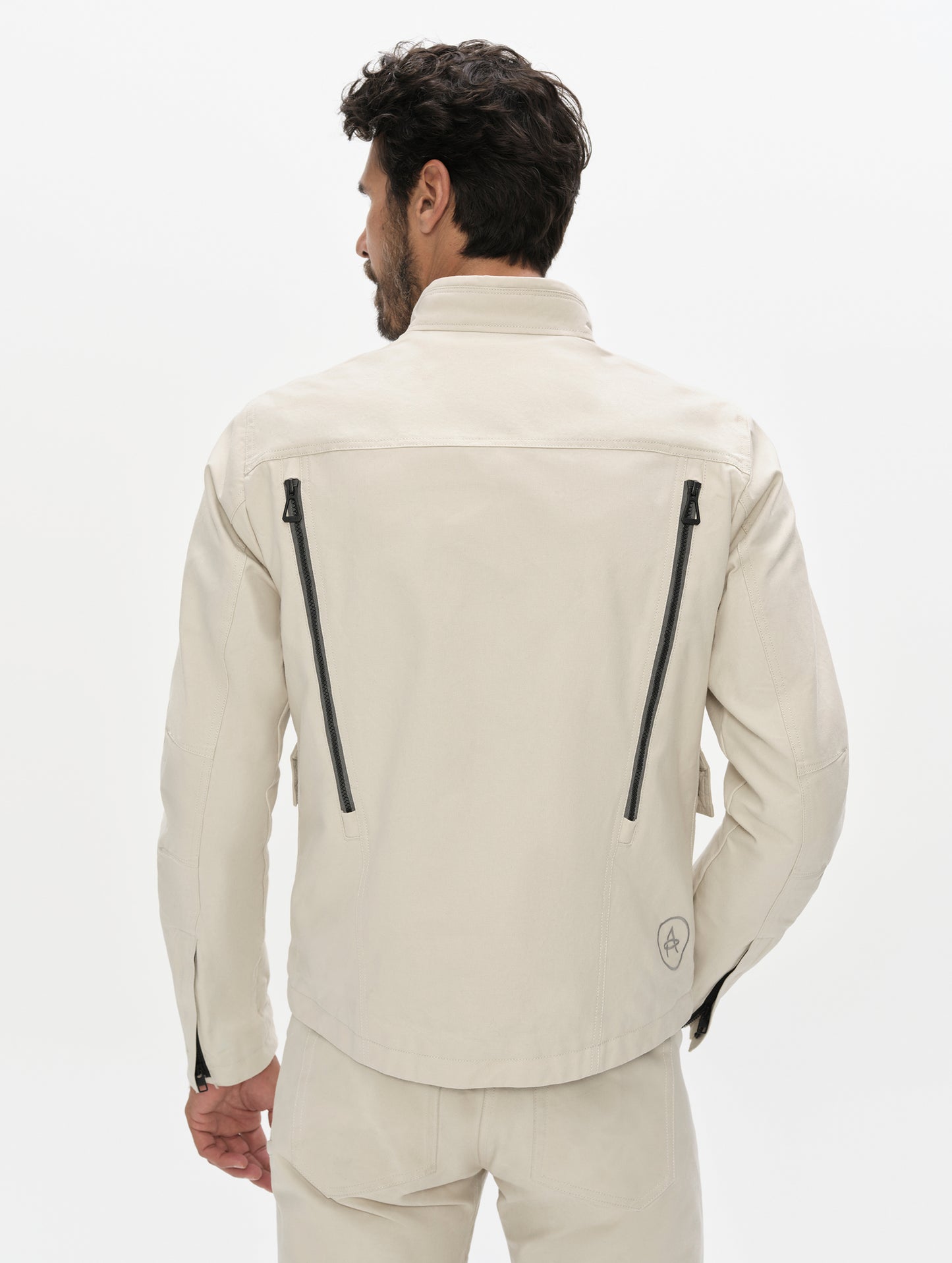 Rear, upper-body view of man wearing the Mojave Motorcycle Jacket 2.0 in Bone from AETHER Apparel.