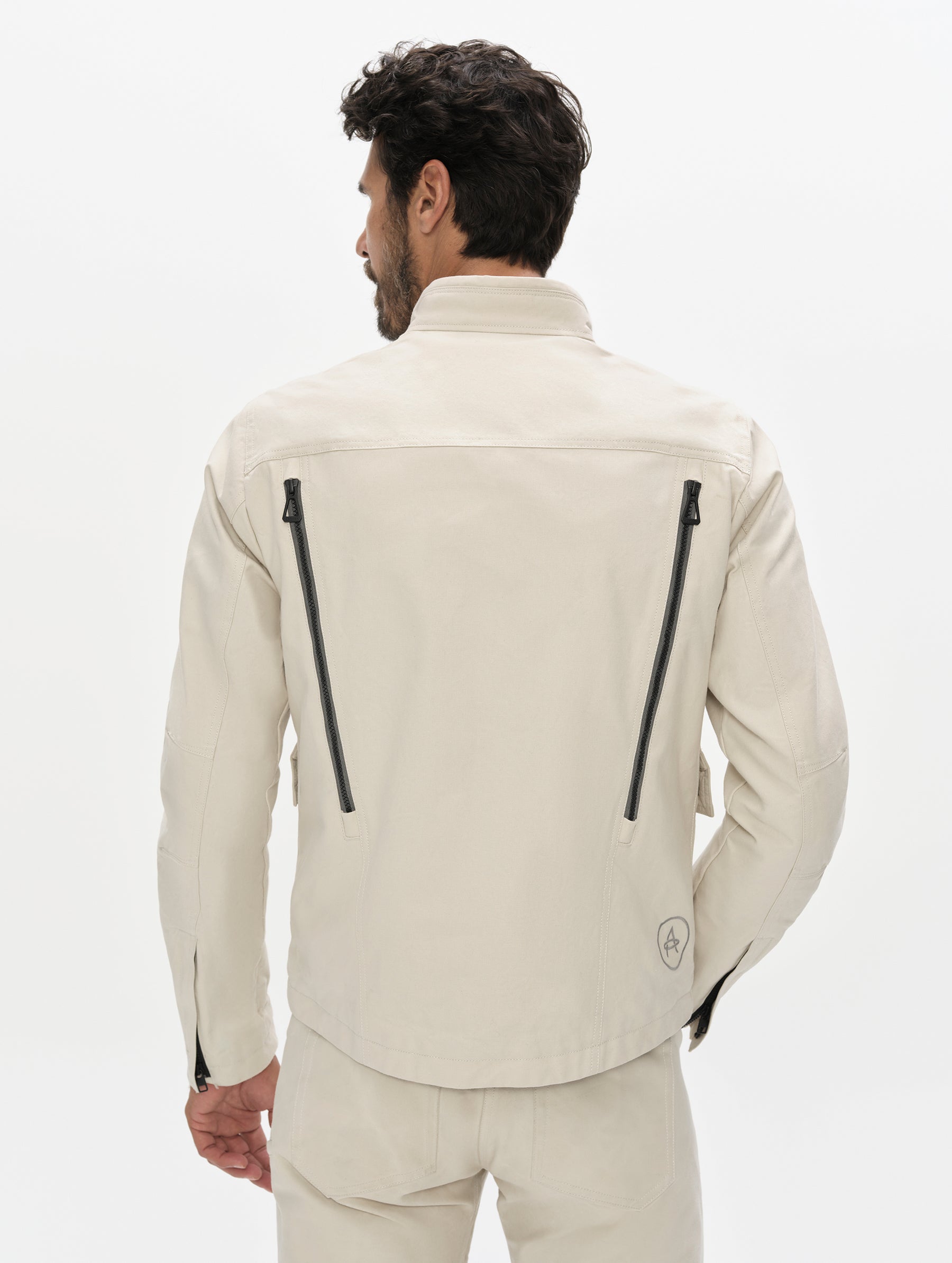 Rear, upper-body view of man wearing the Mojave Motorcycle Jacket 2.0 in Bone from AETHER Apparel.