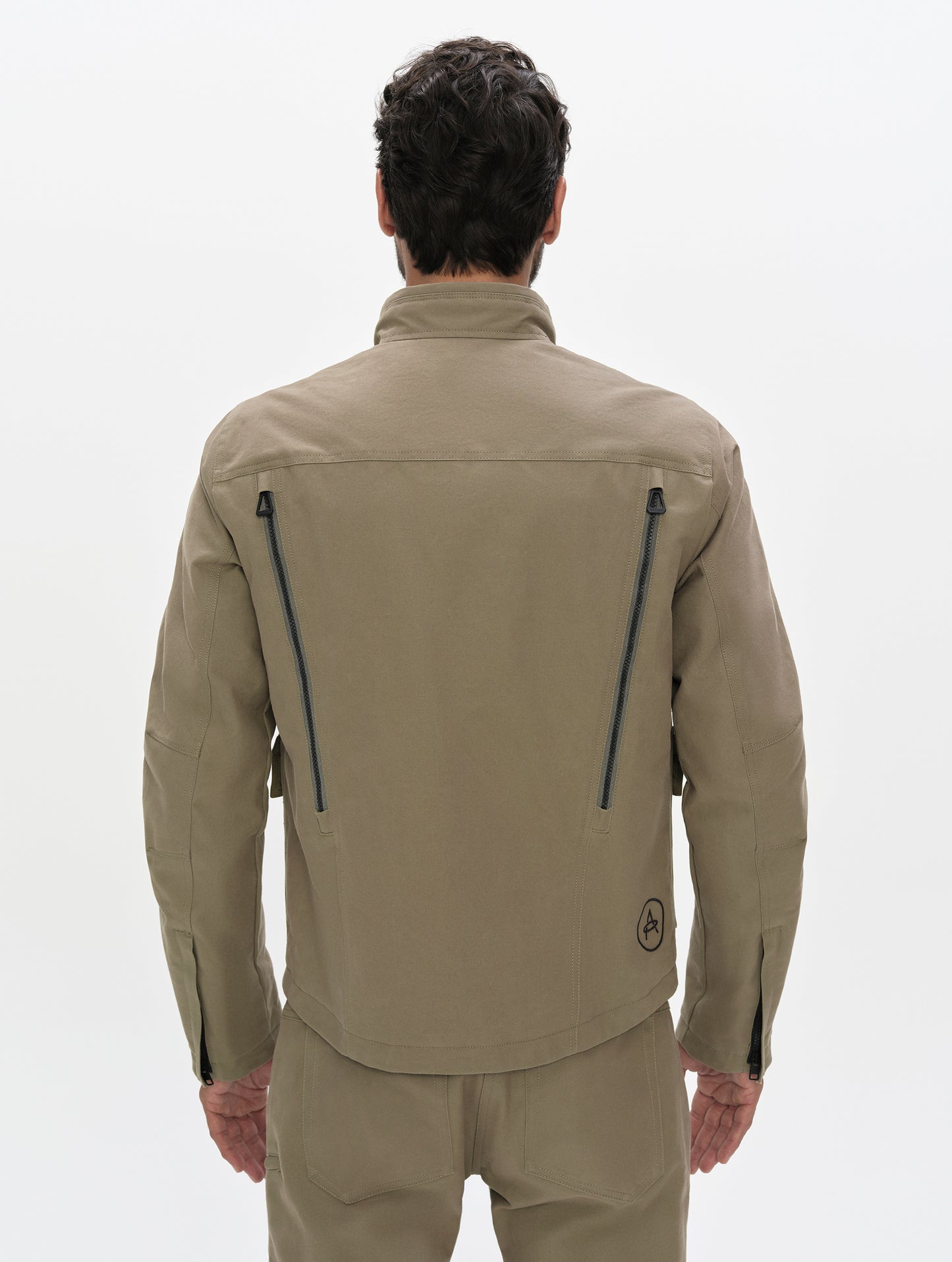 Rear, upper-body view of man wearing the Mojave Motorcycle Jacket 2.0 in Stone Brown from AETHER Apparel.