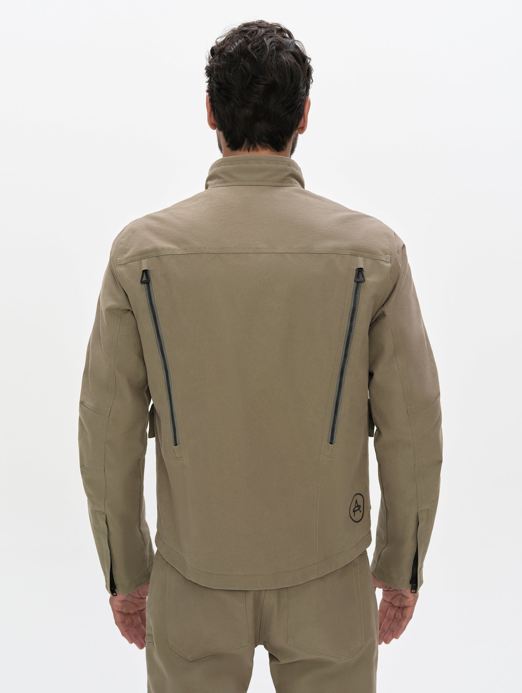 Rear, upper-body view of man wearing the Mojave Motorcycle Jacket 2.0 in Stone Brown from AETHER Apparel.