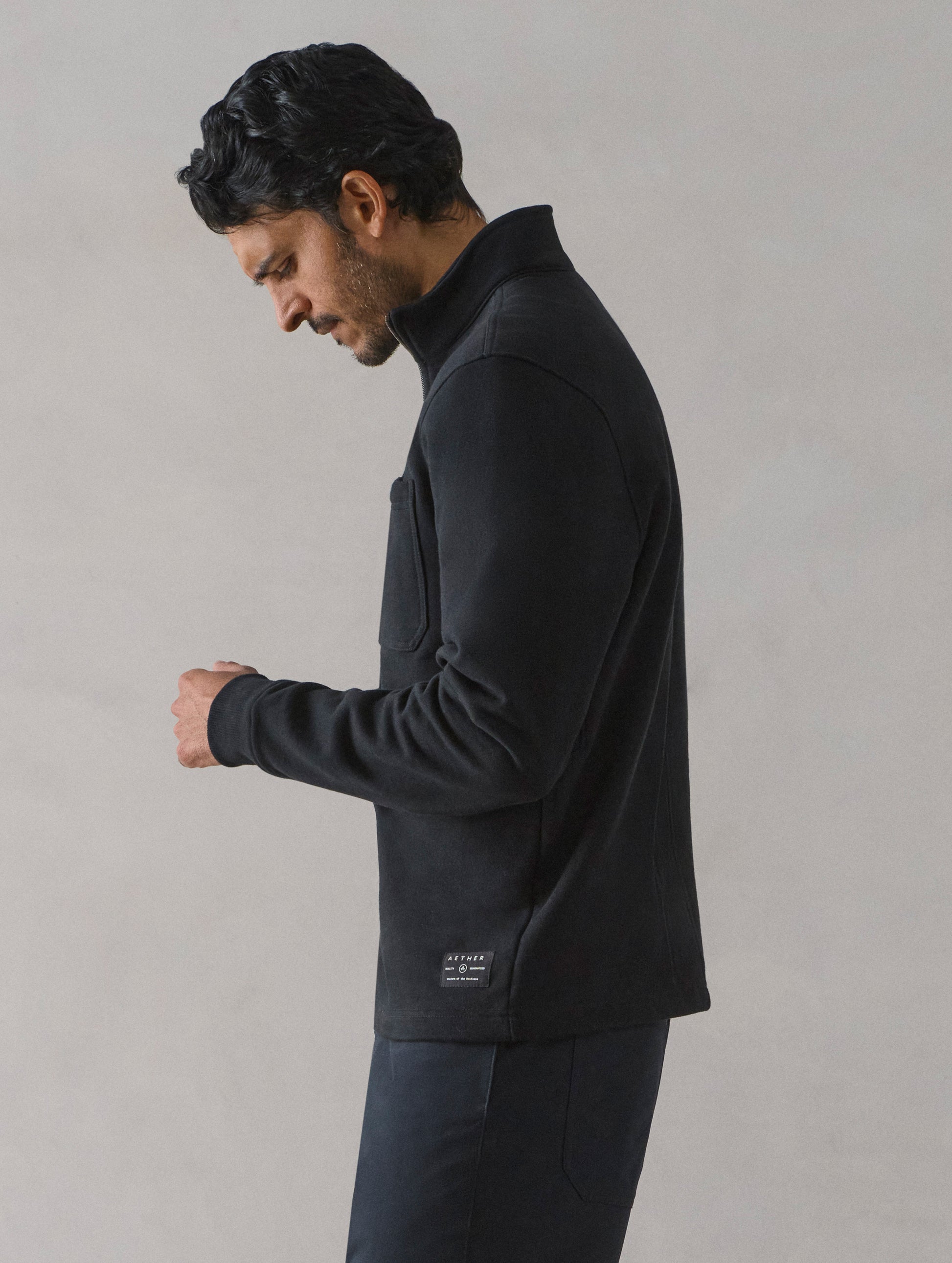 Side profile view of man wearing Monte Half-Zip Sweatshirt in Onyx Black from AETHER Apparel.
