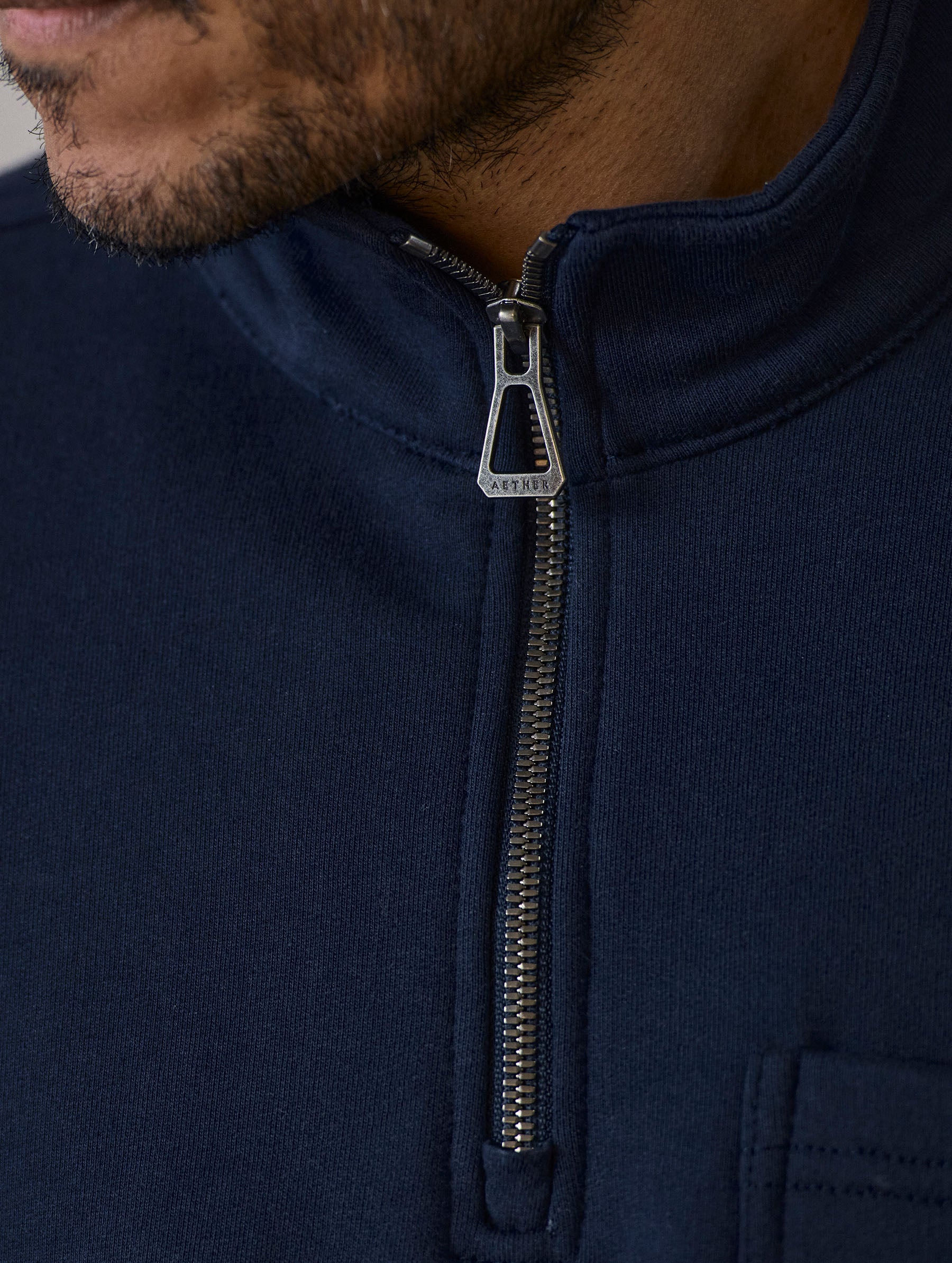 Closeup detailed view of the half-zip center-front closure on the Monte Half-Zip Sweatshirt in Total Eclipse dark blue from AETHER Apparel.