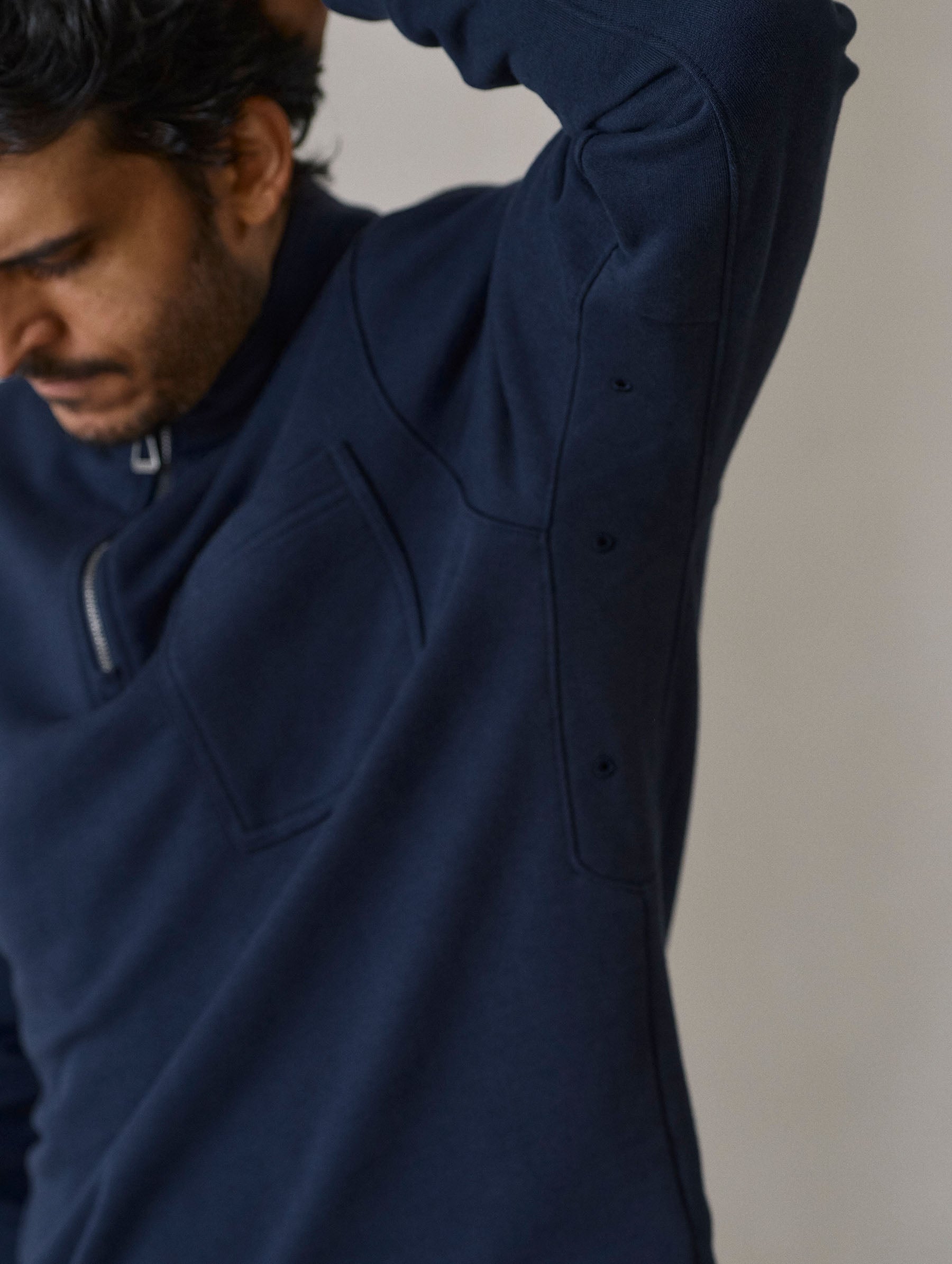 Closeup detailed view of the embroidered underarm eyelets on the Monte Half-Zip Sweatshirt in Total Eclipse dark blue from AETHER Apparel.