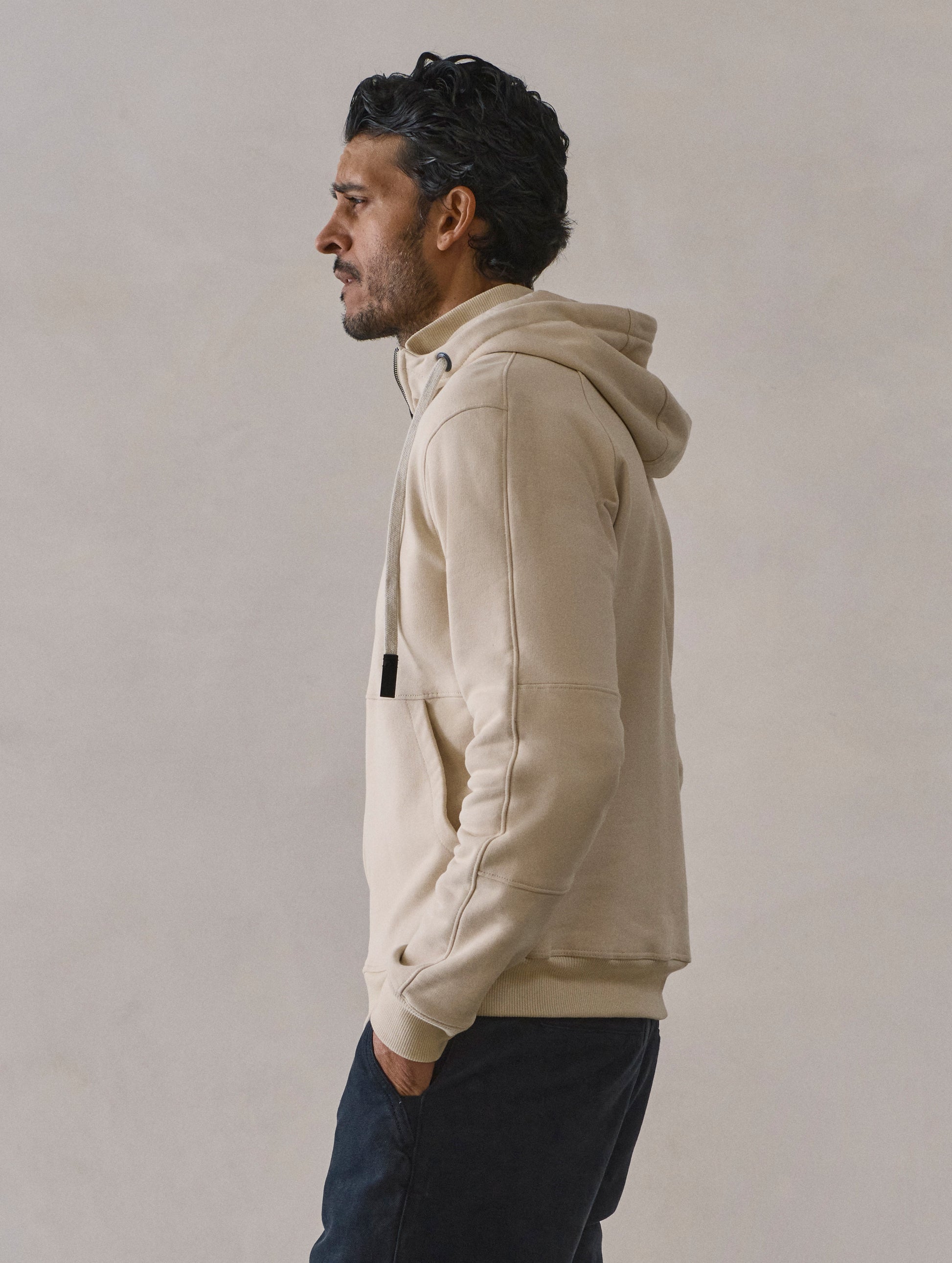 Side profile view of man wearing Monte Full-Zip Hoodie in Bone white from AETHER Apparel.