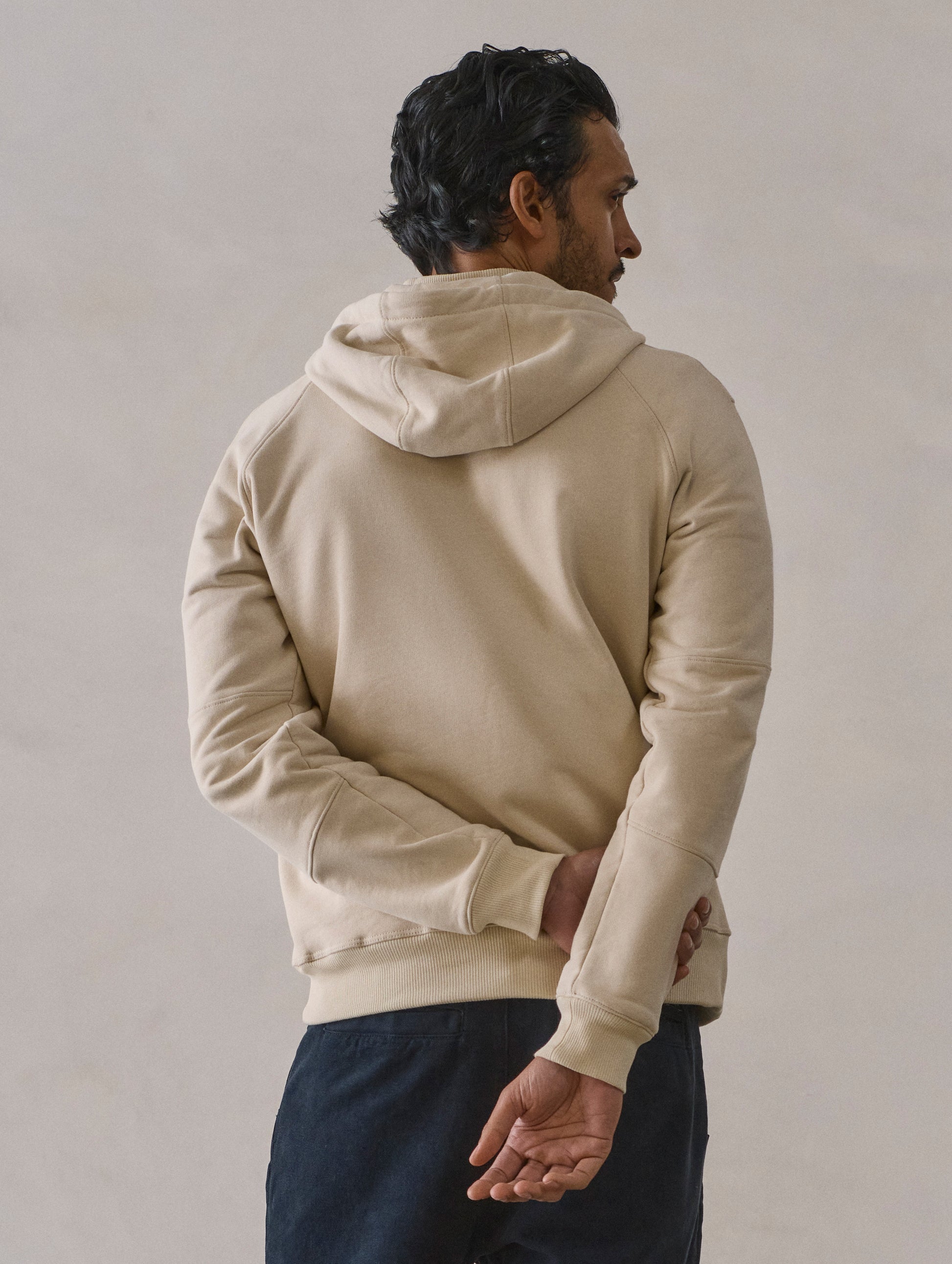 Rear view of man wearing Monte Full-Zip Hoodie in Bone white from AETHER Apparel.