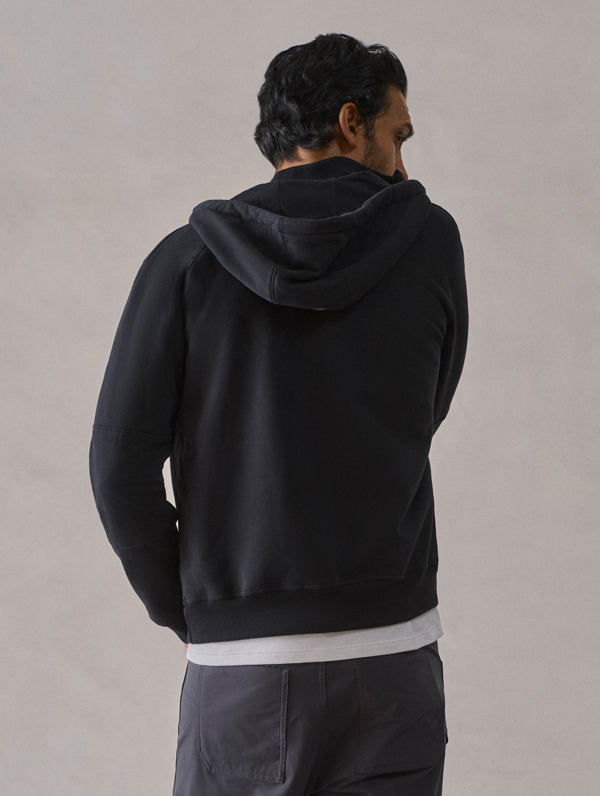 Rear upper-body view of man wearing Monte Full-Zip Hoodie in Onyx Black from AETHER Apparel.