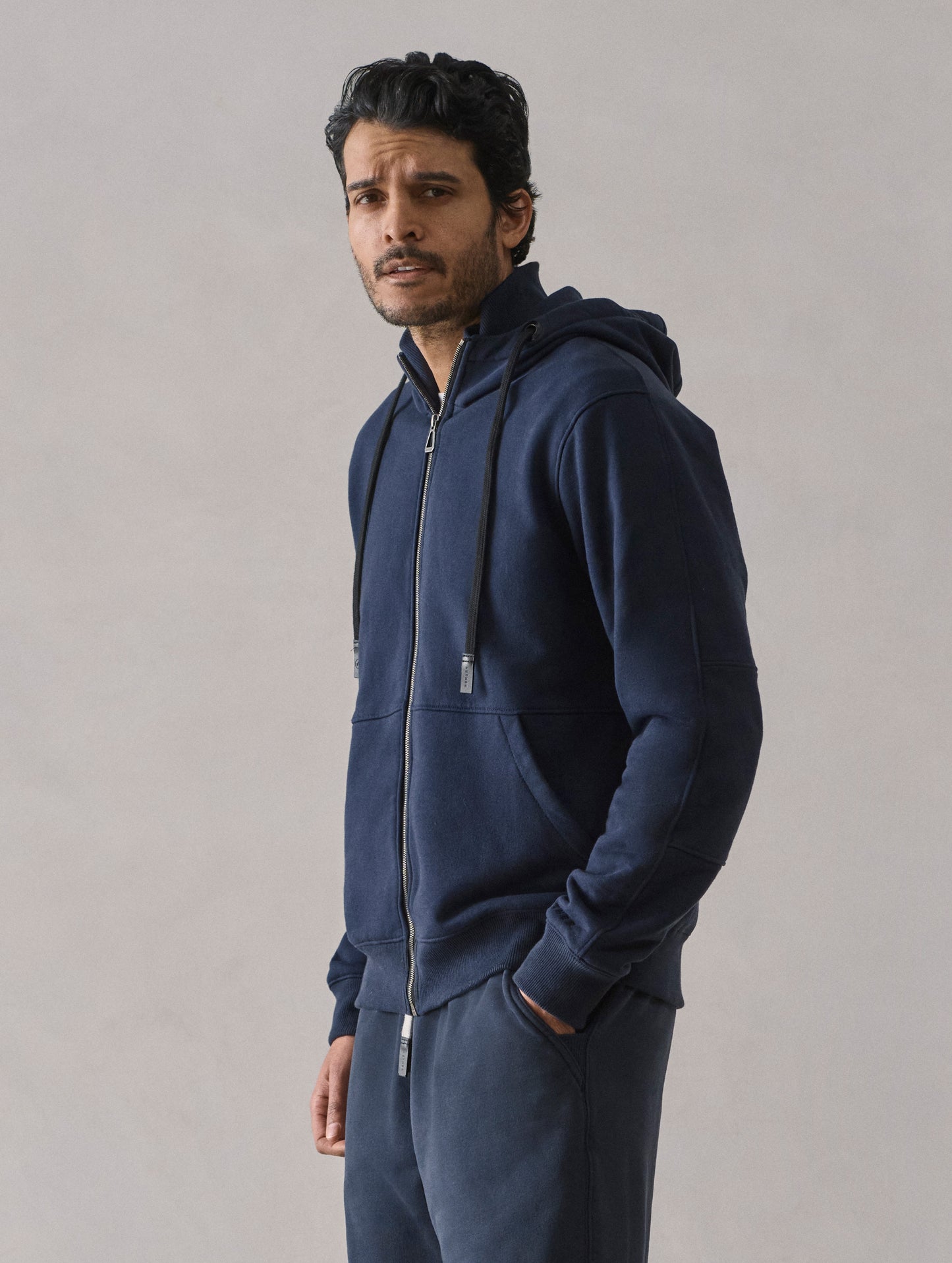 Front 3/4 body view of man wearing Monte Full-Zip Hoodie in Total Eclipse dark blue from AETHER Apparel.