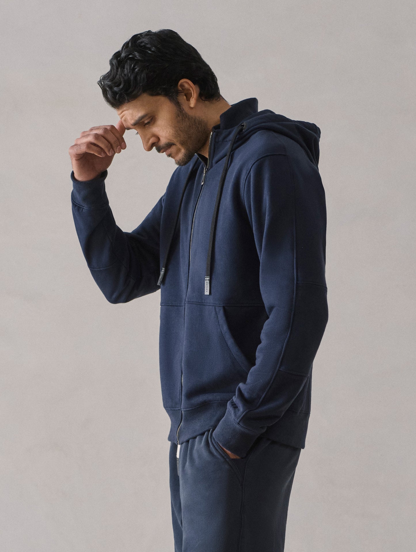 Side profile view of man wearing Monte Full-Zip Hoodie in Total Eclipse dark blue from AETHER Apparel.