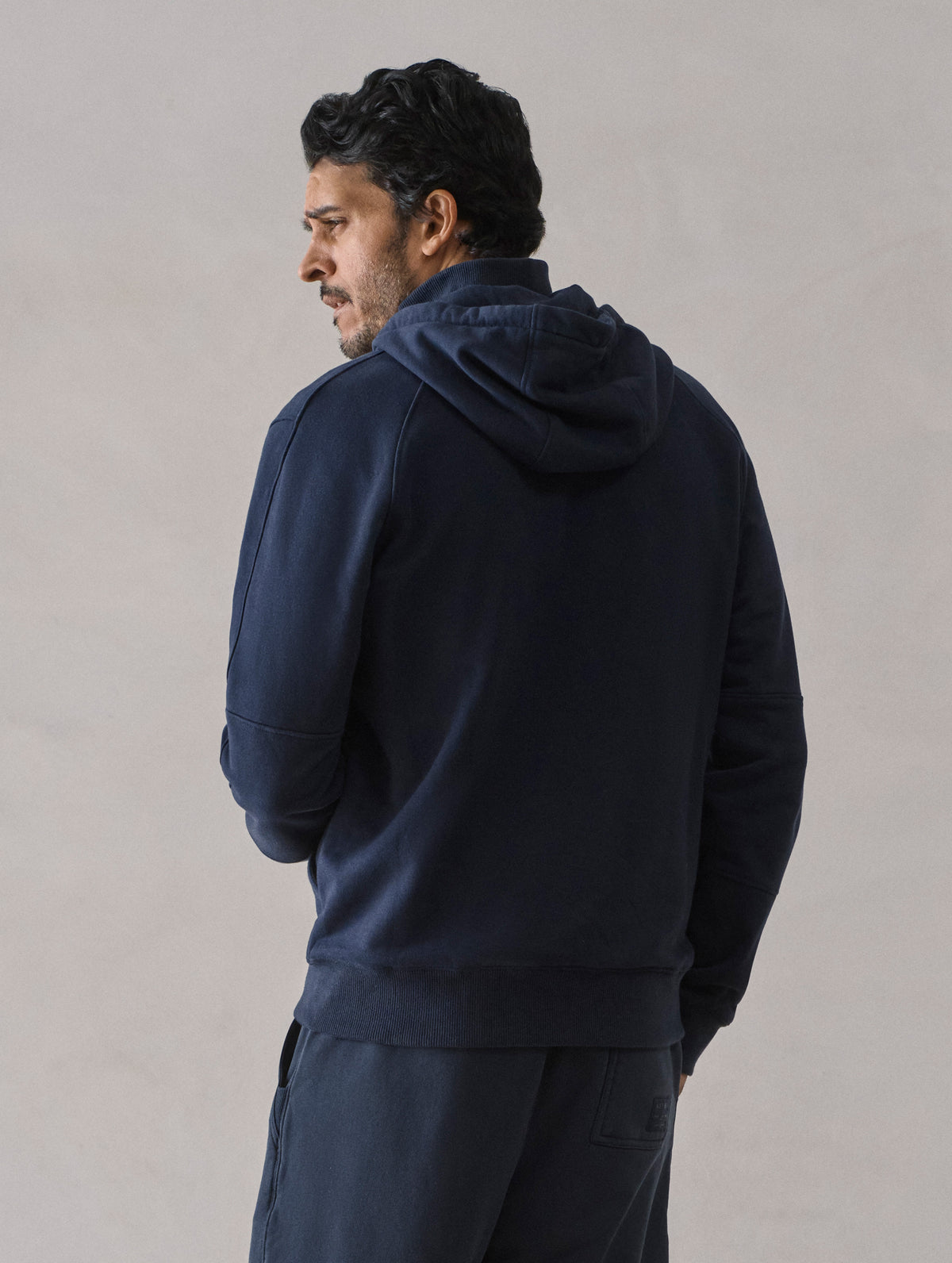 Rear view of man wearing Monte Full-Zip Hoodie in Total Eclipse dark blue from AETHER Apparel.