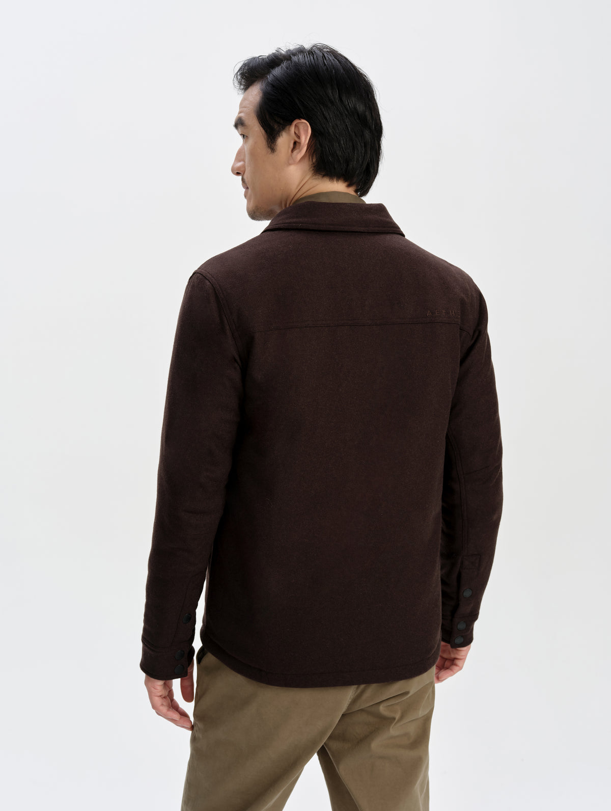 Rear upper-body view of man wearing the Nova Insulated Button-Down in Ash Brown from AETHER Apparel.