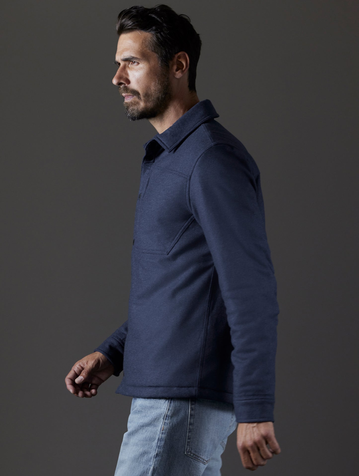 Side profile body view of man wearing Nova Insulated Button-Down in Total Eclipse Heather dark blue from AETHER Apparel.