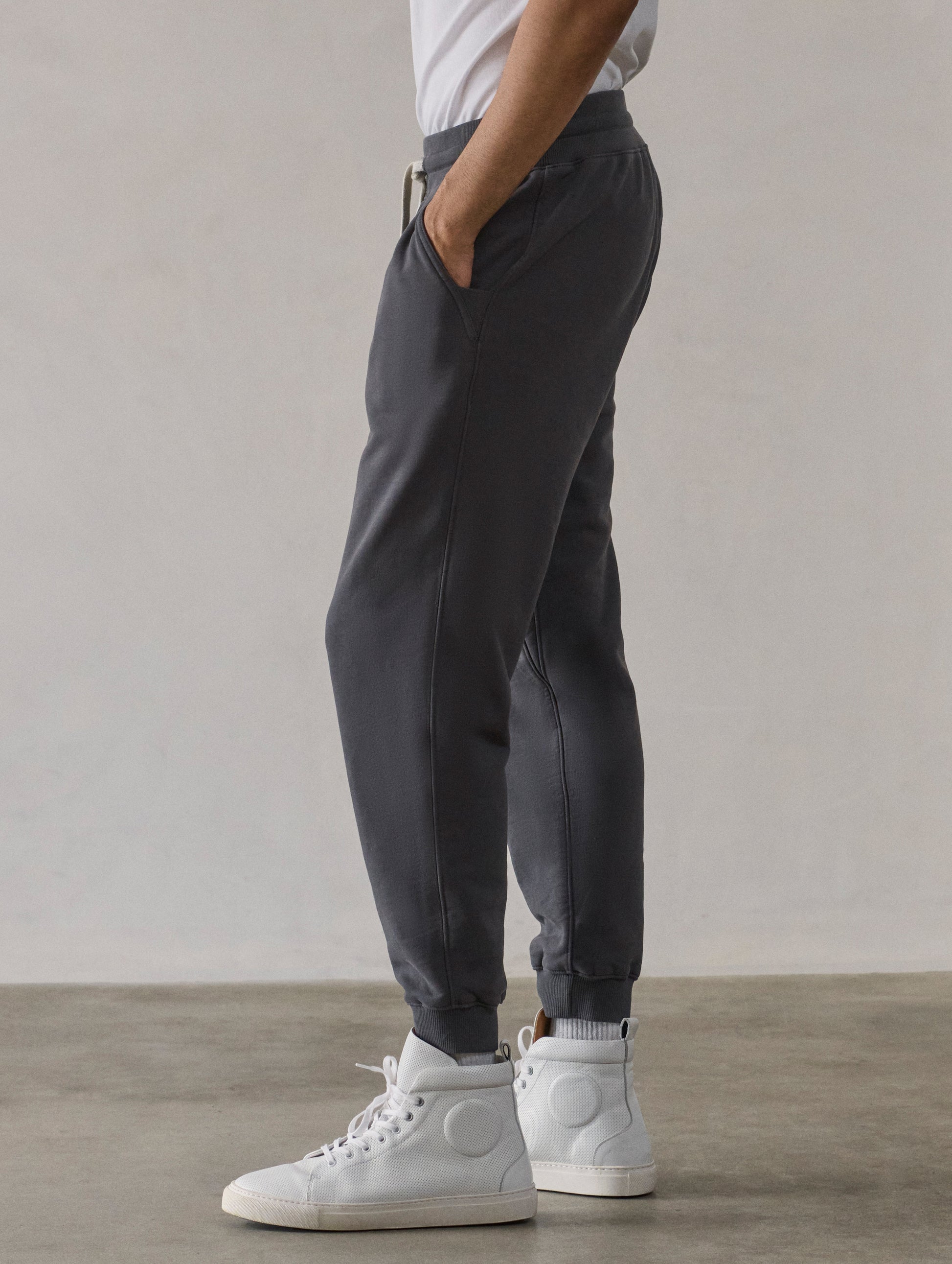 Left side profile lower-body view of man wearing Osa Cuffed Sweatpant in Graphite grey from AETHER Apparel.
