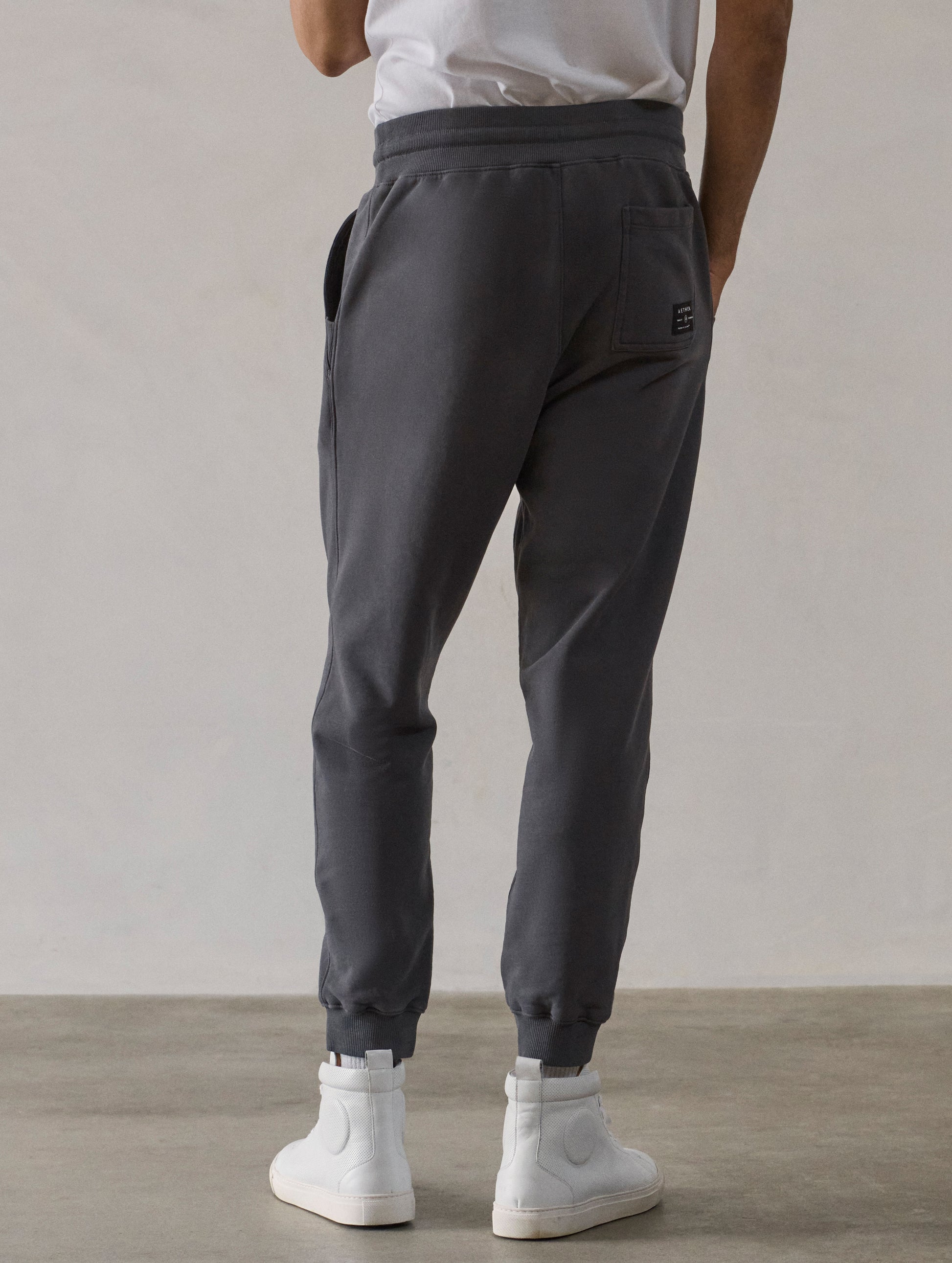Rear lower-body view of man wearing Osa Cuffed Sweatpant in Graphite grey from AETHER Apparel.