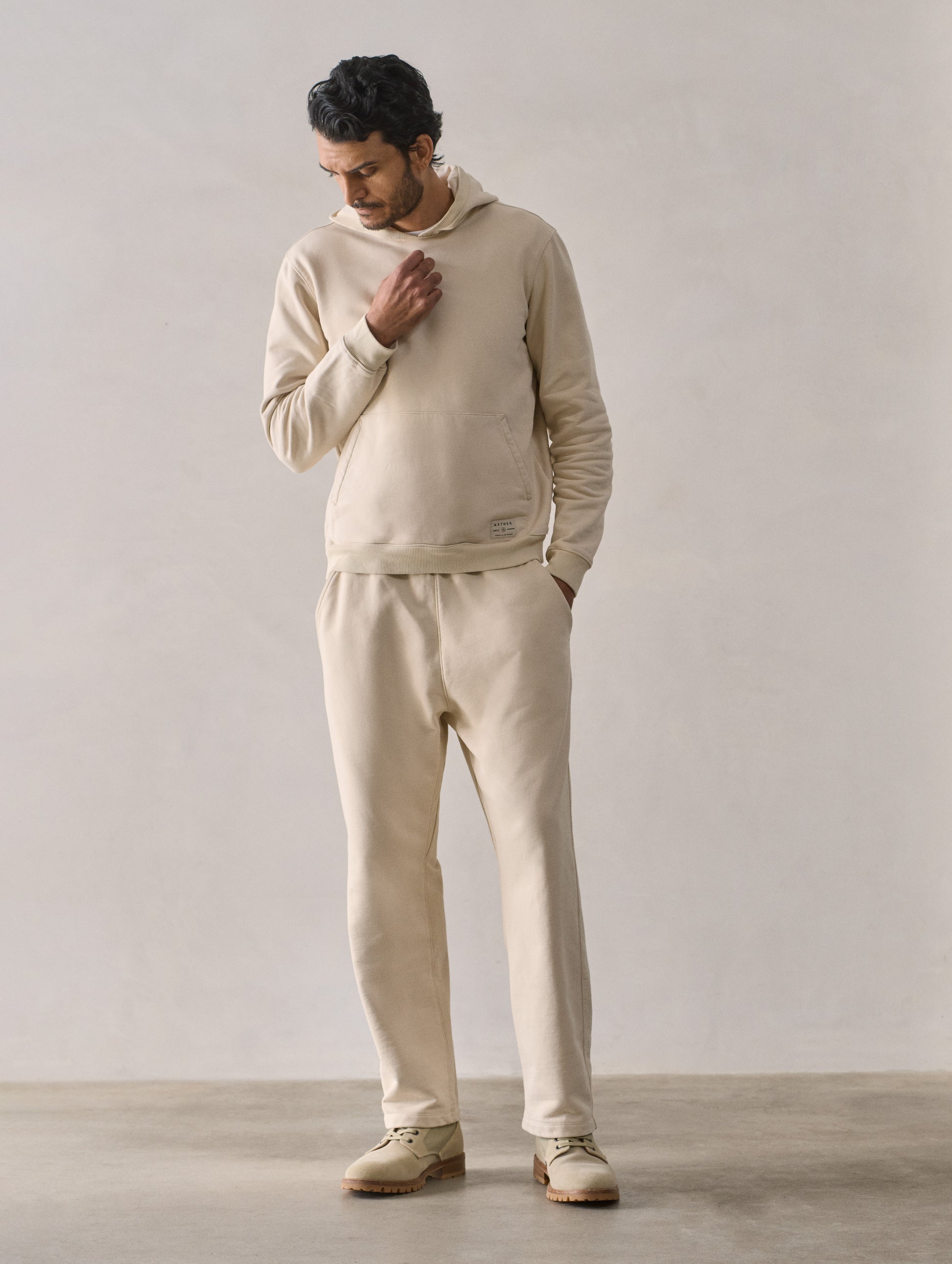 Front full-body view of man wearing Osa Pullover Hoodie in Bone white from AETHER Apparel.