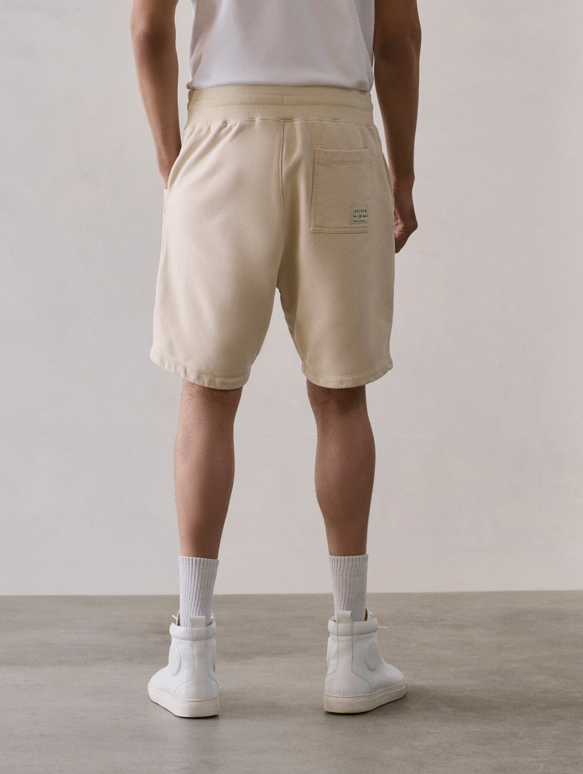 Rear lower body view of man wearing Osa Sweatshort in Bone white from AETHER Apparel.