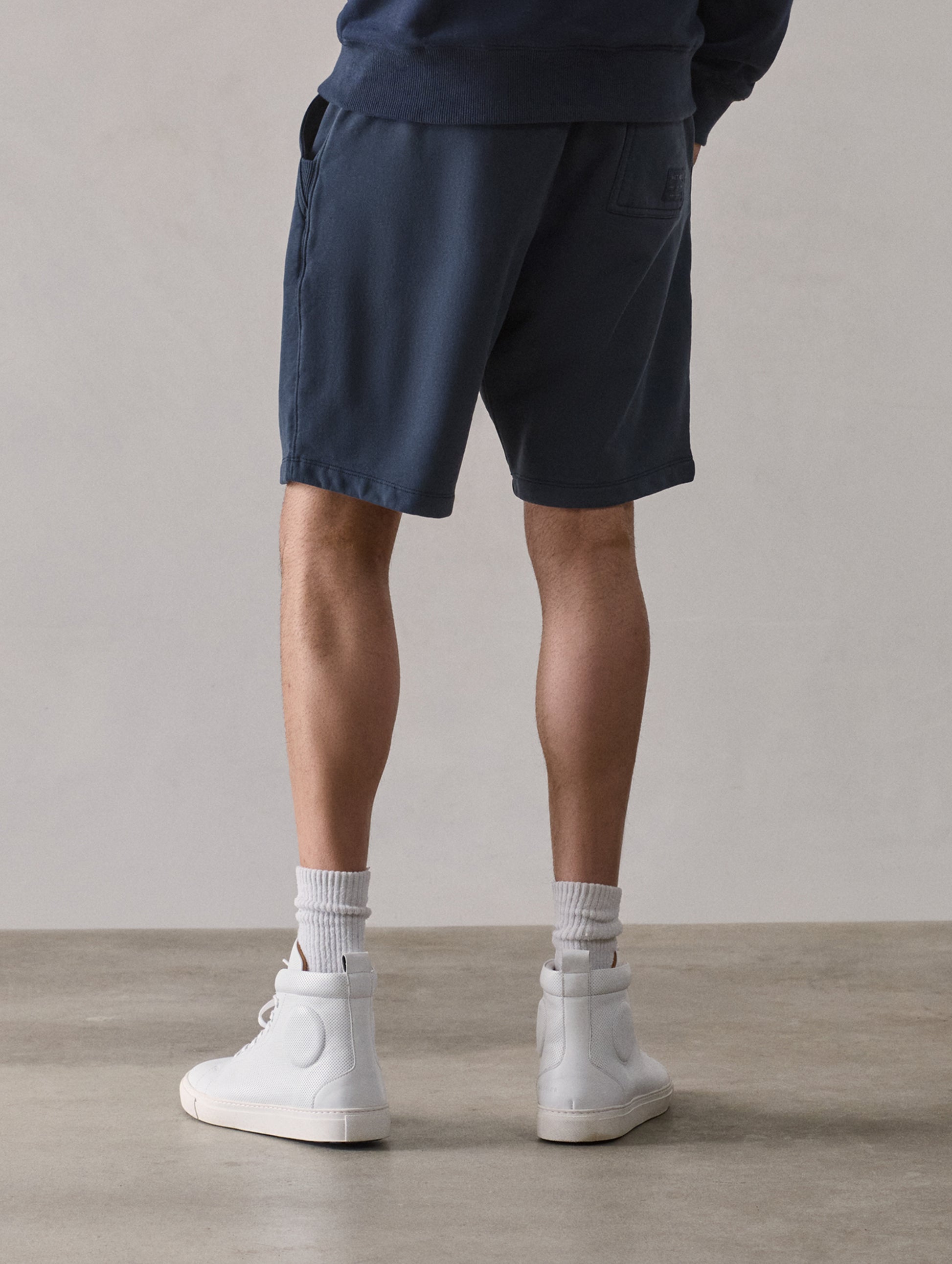 Rear lower body view of man wearing Osa Sweatshort in Total Eclipse dark blue from AETHER Apparel.
