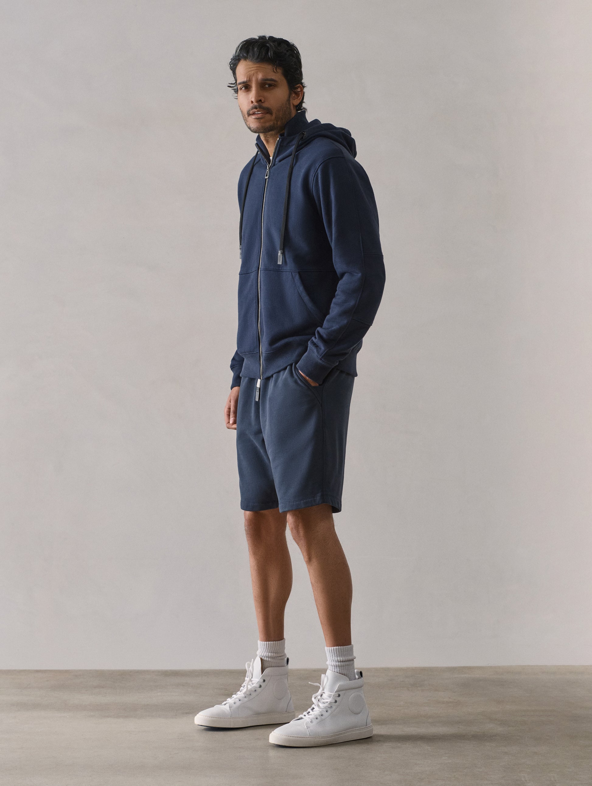 Front 3/4 full-body view of man wearing Osa Sweatshort in Total Eclipse dark blue from AETHER Apparel.
