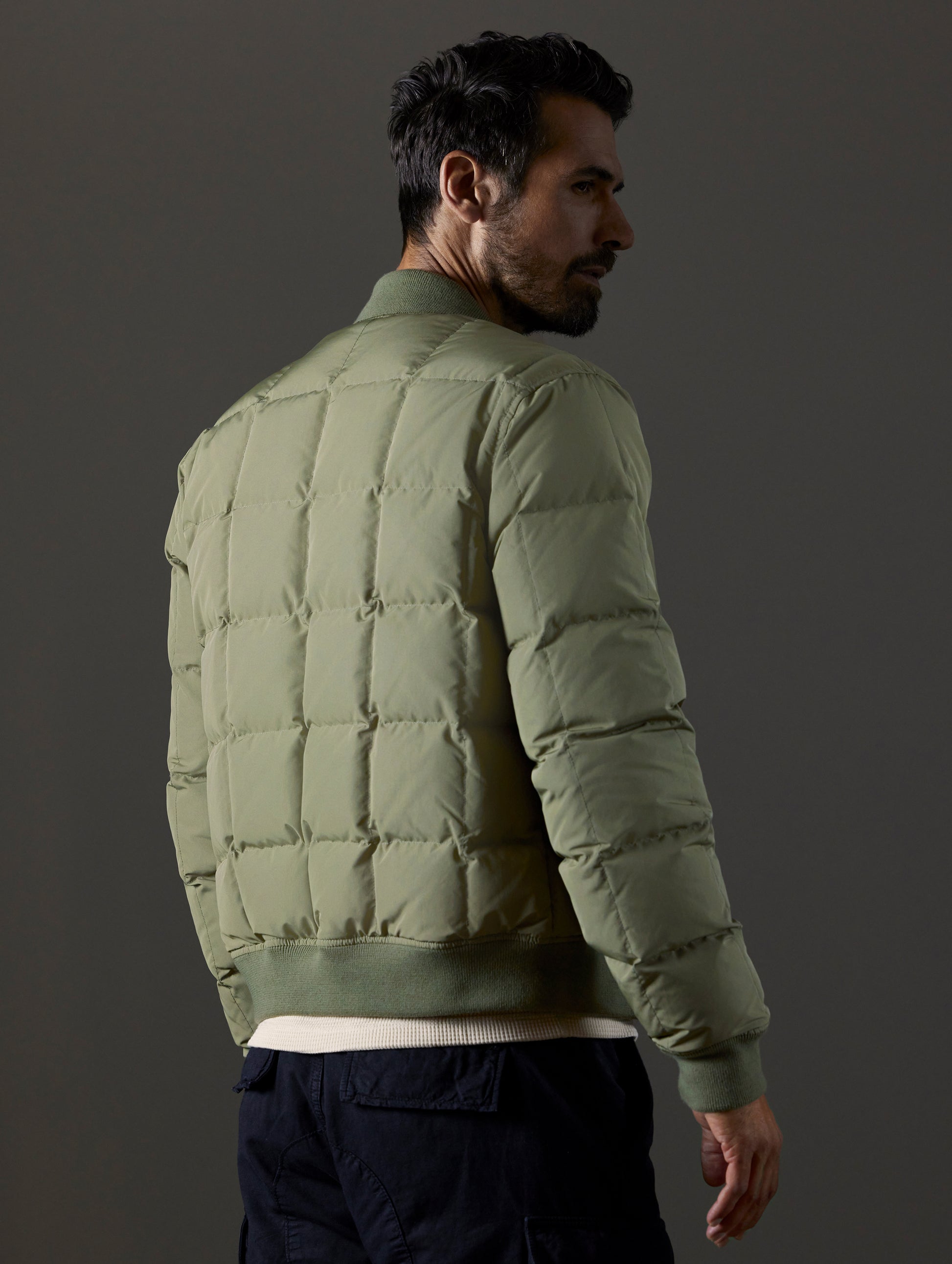 Rear 3/4 body view of man wearing Pacer Jacket in Fern Green from AETHER Apparel.