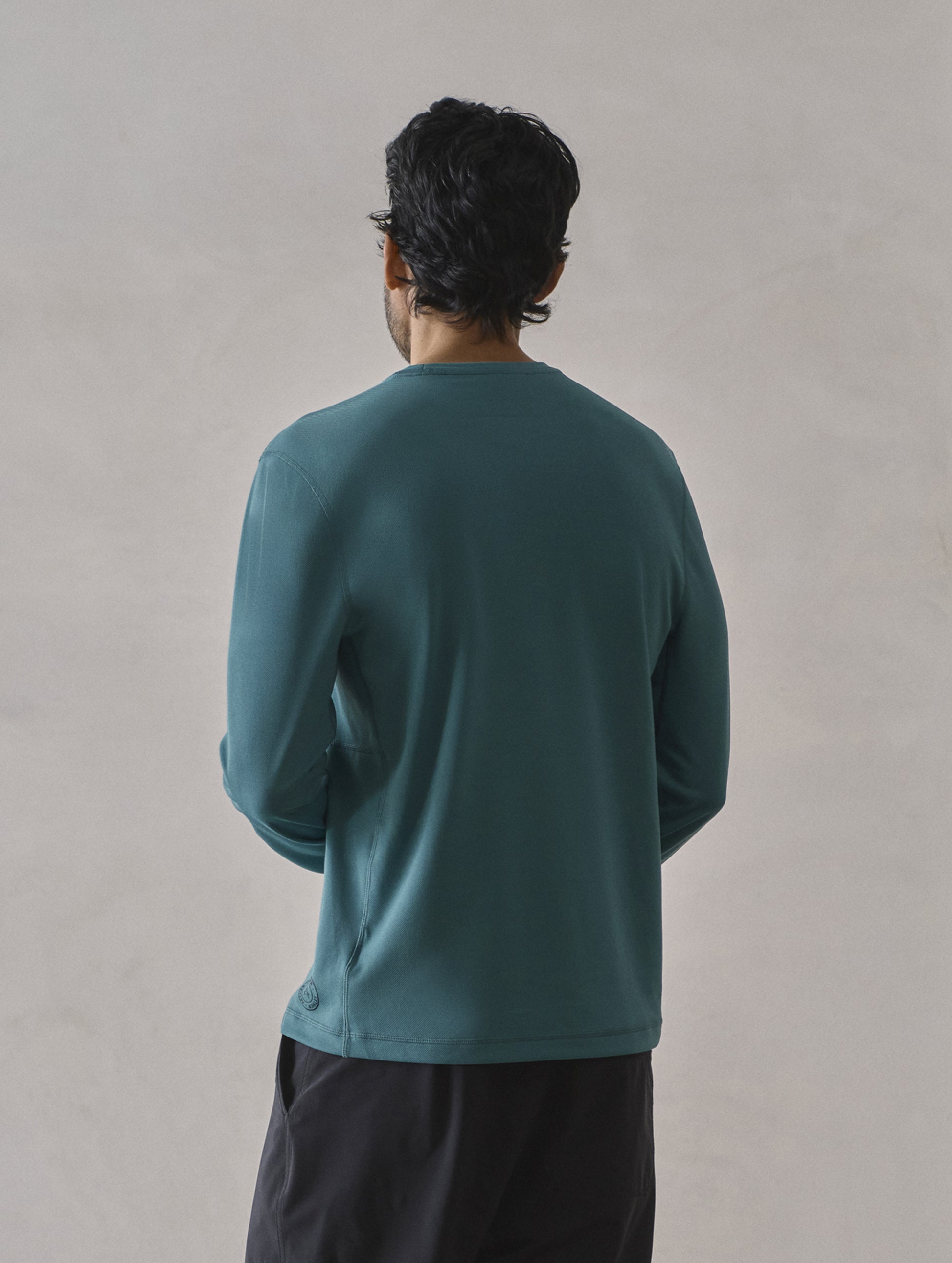 Rear 3/4 upper-body view of man wearing Pacific Crewneck Sun Shirt in Aqua Blue from AETHER Apparel.