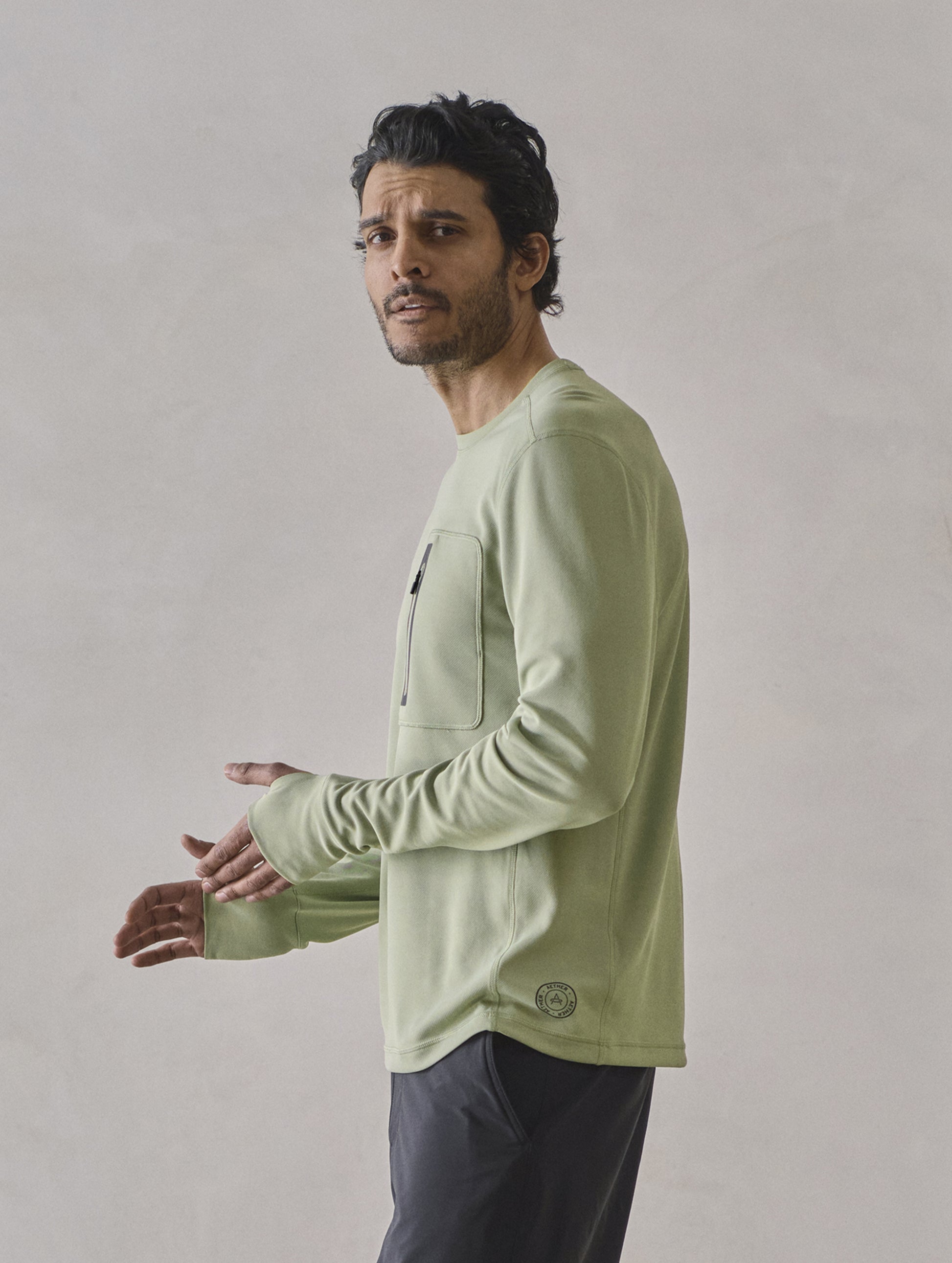 Side profile upper-body view of man wearing Pacific Crewneck Sun Shirt in Sage Green from AETHER Apparel.