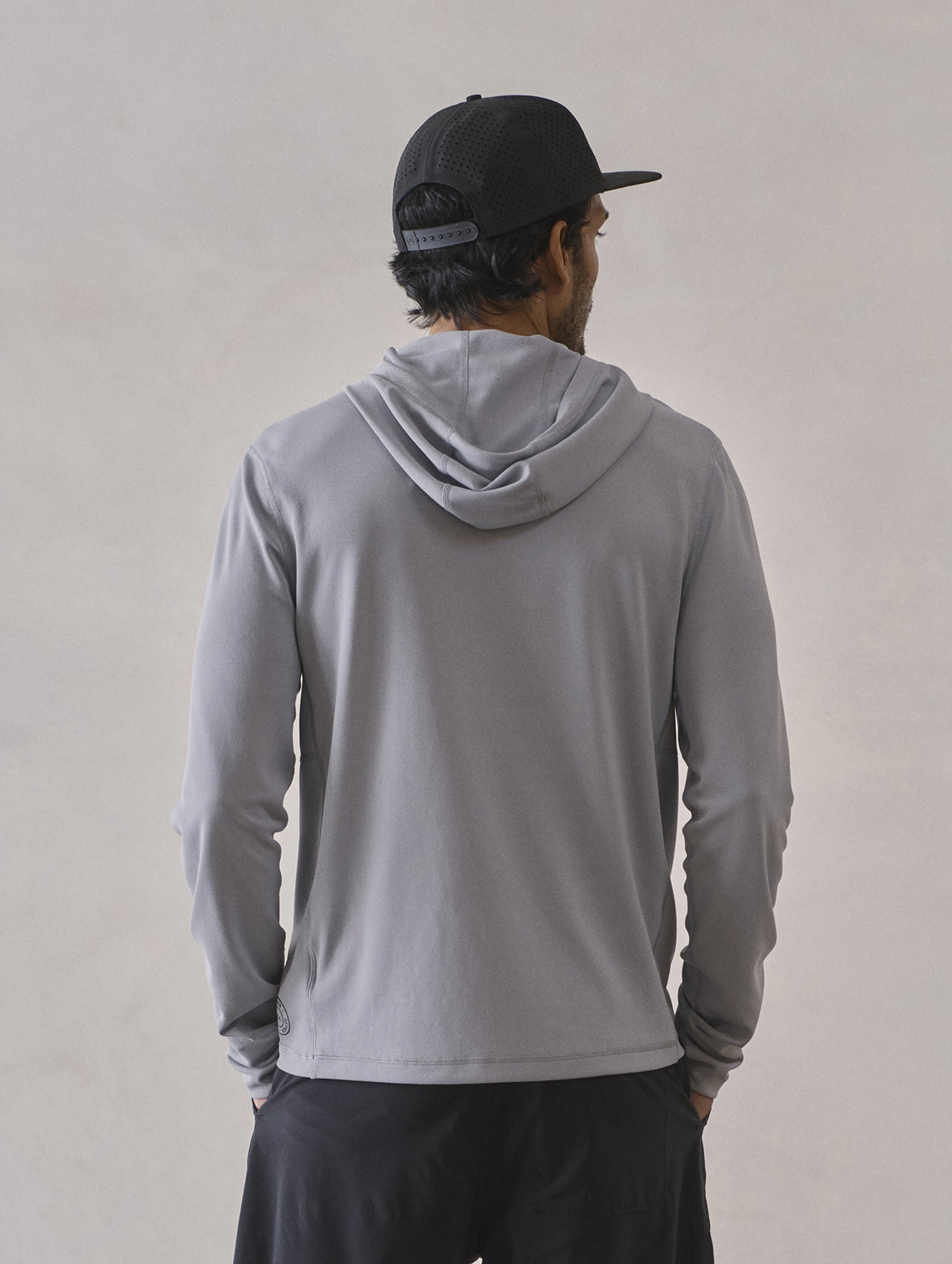 Rear upper-body view of man wearing Pacific Hooded Sun Shirt in Sky Grey from AETHER Apparel.