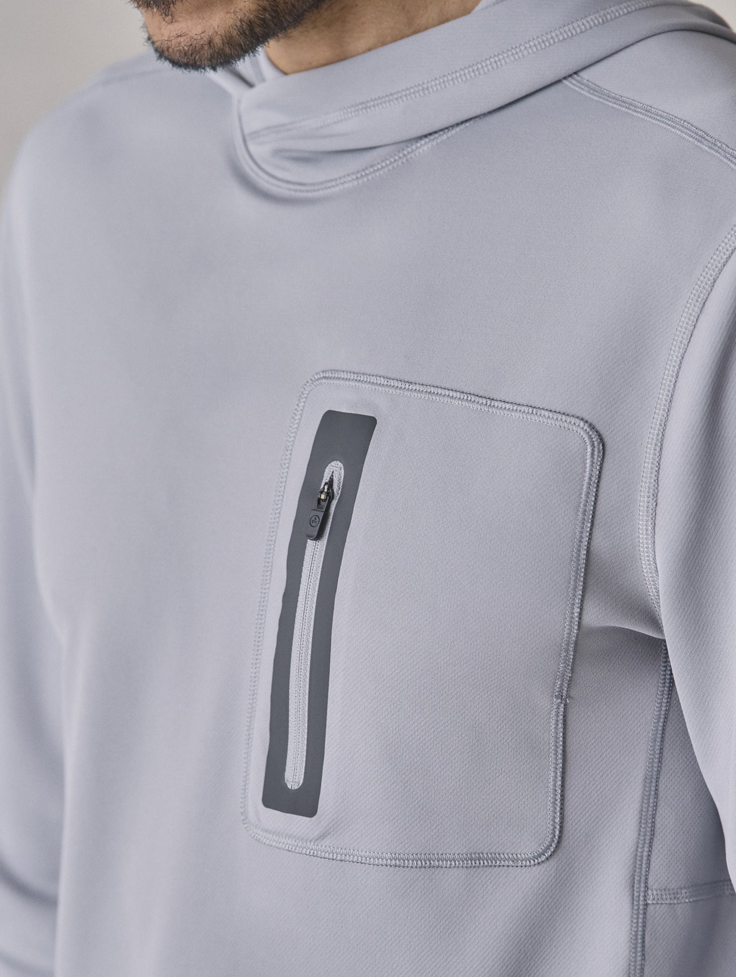 Closeup front 3/4 upper-body view of man wearing Pacific Hooded Sun Shirt in Sky Grey from AETHER Apparel.