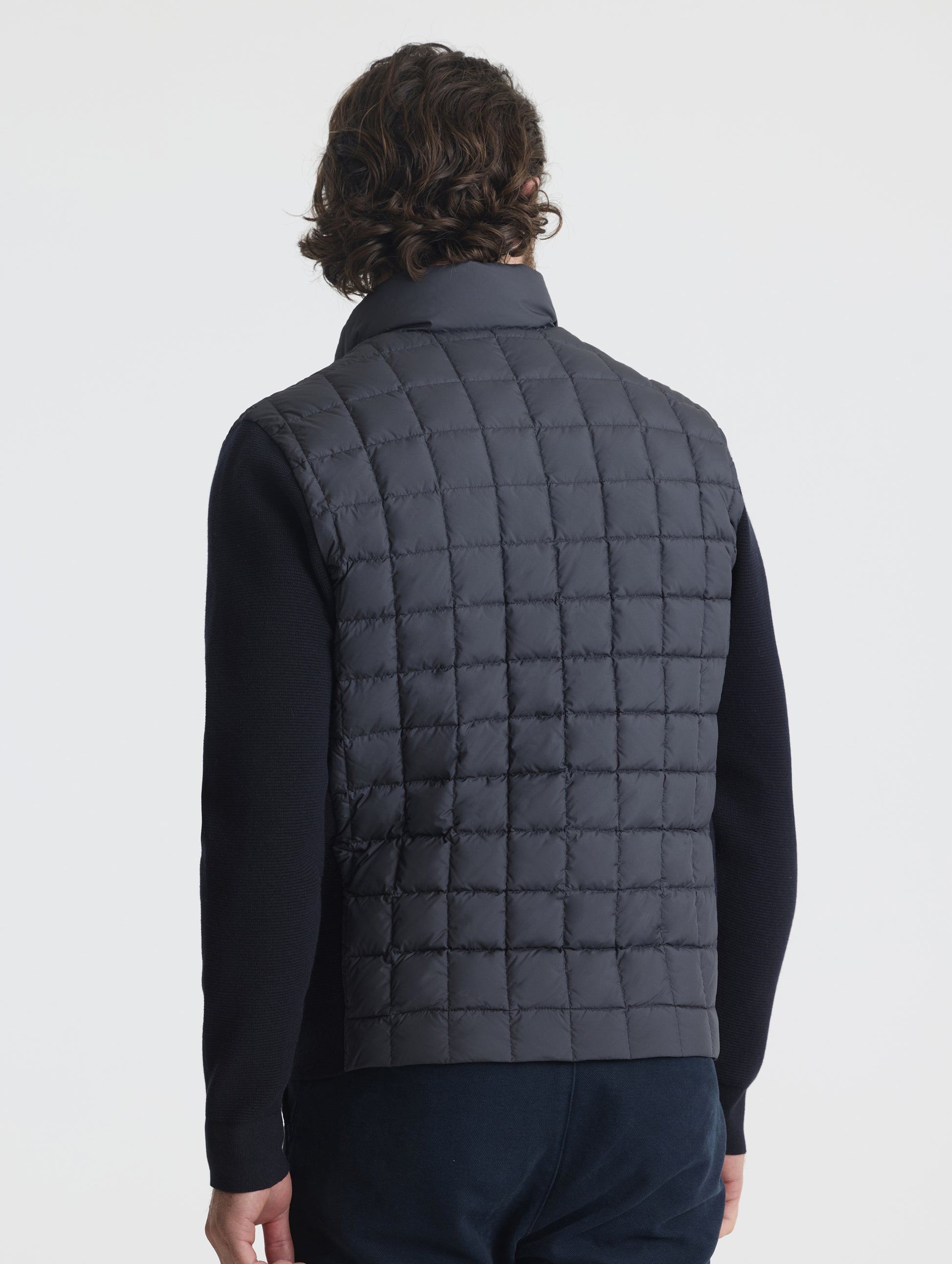 Rear, angled, upper-body view of man wearing M Phase Full-Zip in Onyx Black from AETHER Apparel.