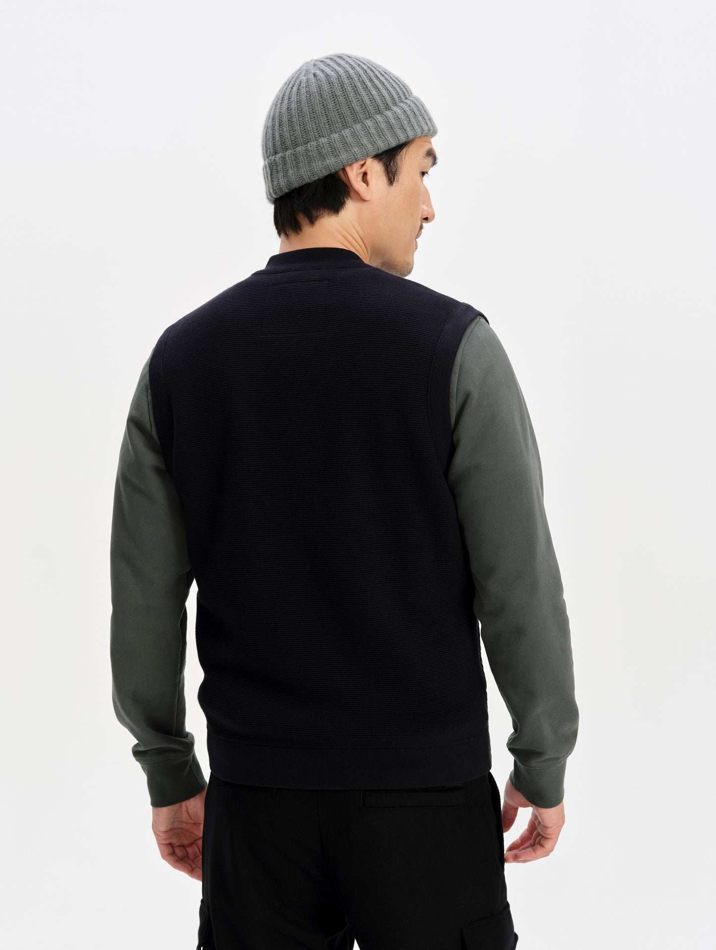 Rear upper-body view of man wearing the M Phase Vest in Onyx Black from AETHER Apparel. 