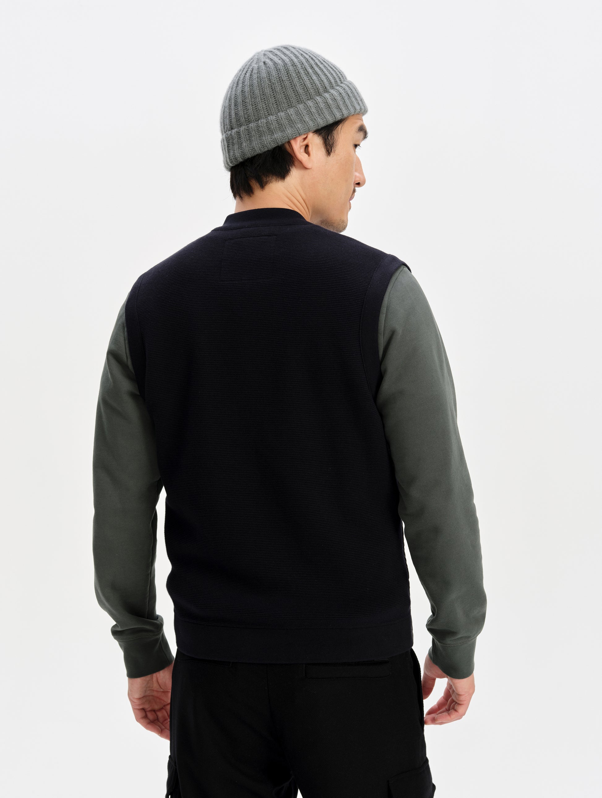 Rear upper-body view of man wearing the M Phase Vest in Onyx Black from AETHER Apparel. 
