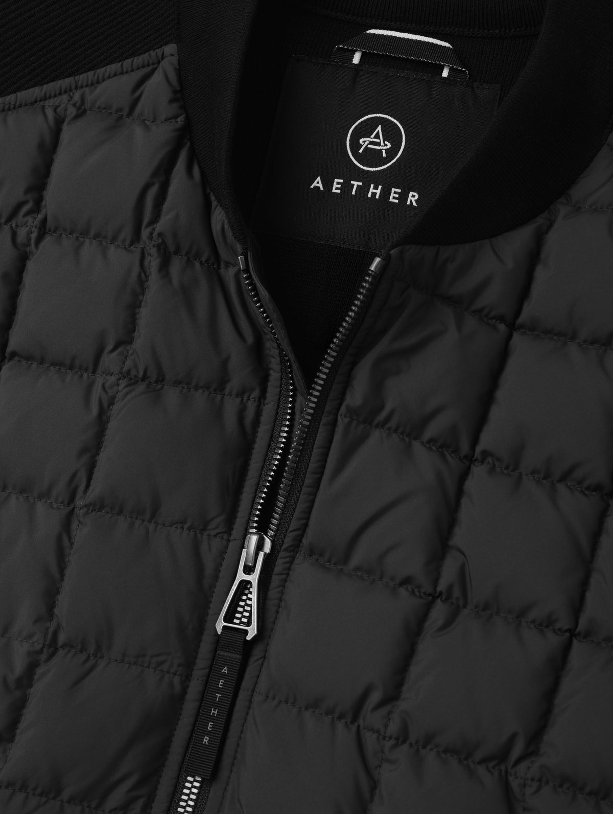 Closeup detailed view of the main center-front zipper and rib-knit collar on the M Phase Vest in Onyx Black from AETHER Apparel. 