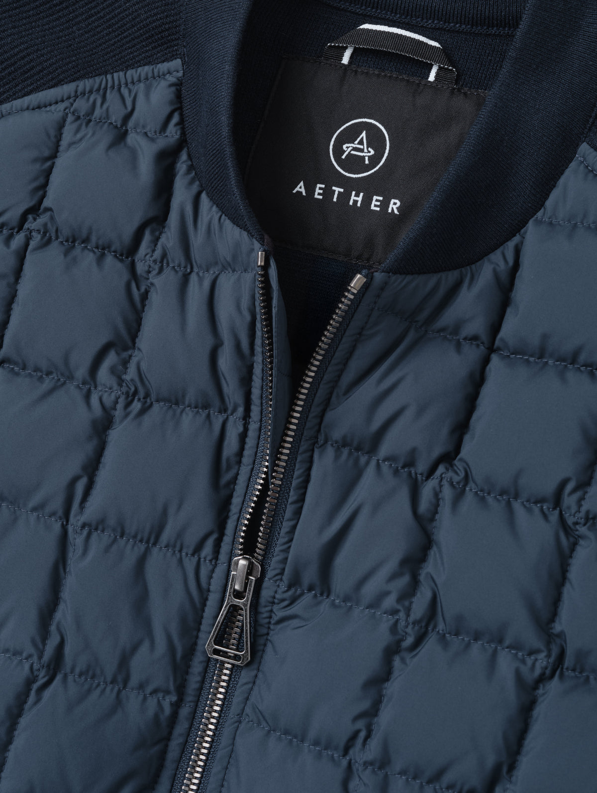 Closeup detailed view of the main center-front zipper and rib-knit collar on the M Phase Vest in Total Eclipse from AETHER Apparel. 