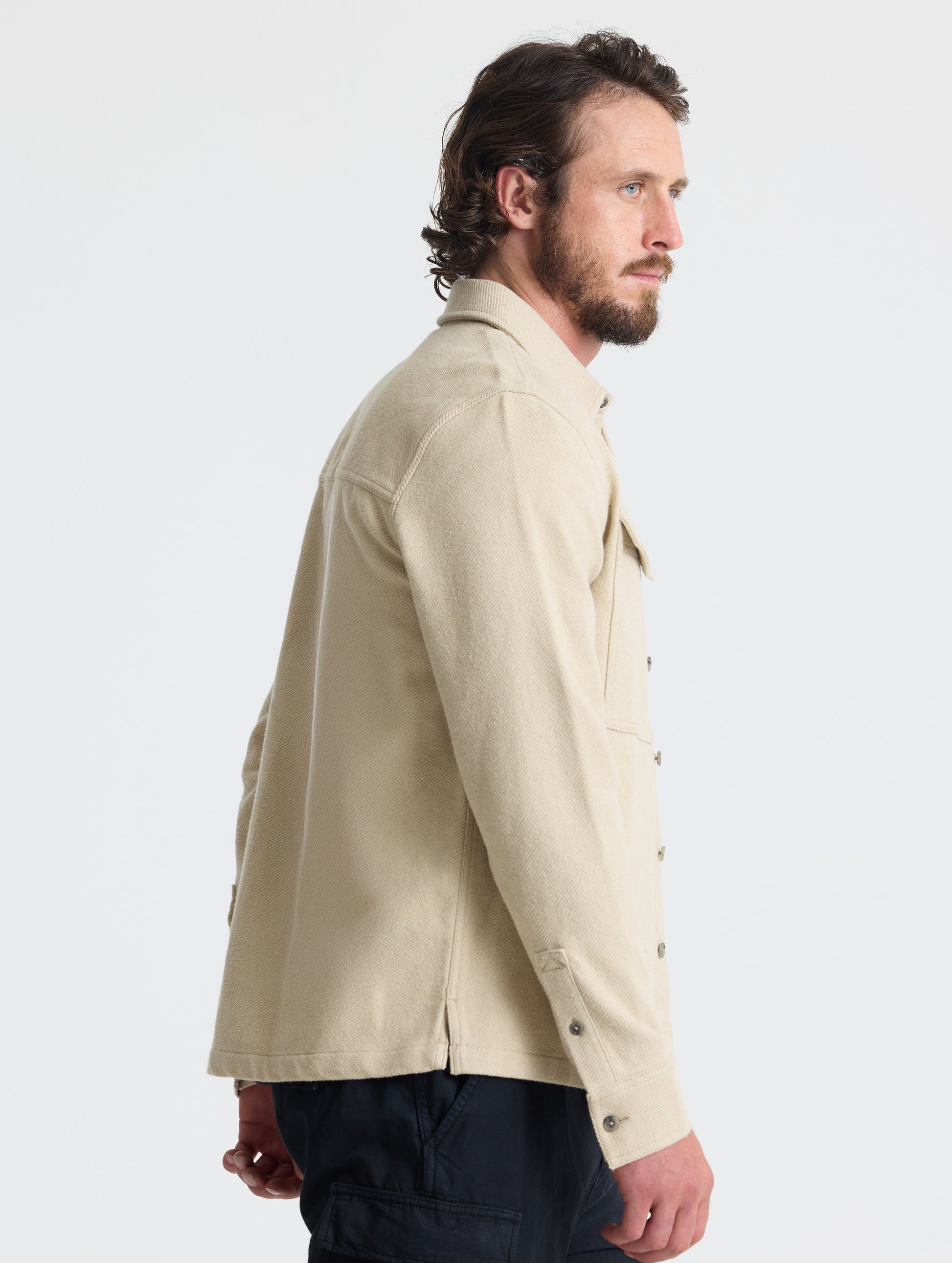 Side profile upper-body view of man wearing Pioneer Heavyweight Button-Down in Bone white from AETHER Apparel.