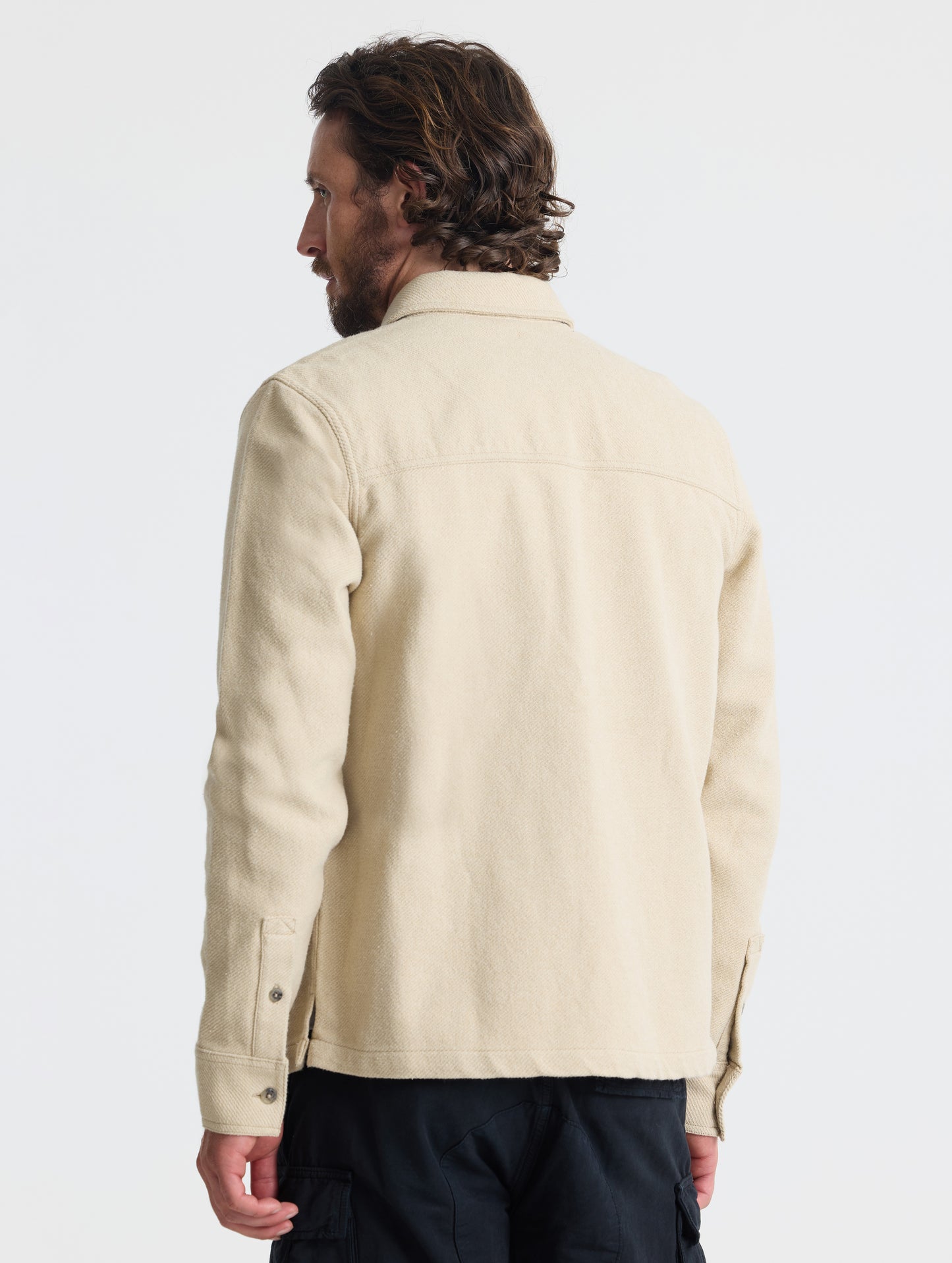 Rear, angled upper-body view of man wearing Pioneer Heavyweight Button-Down in Bone white from AETHER Apparel.
