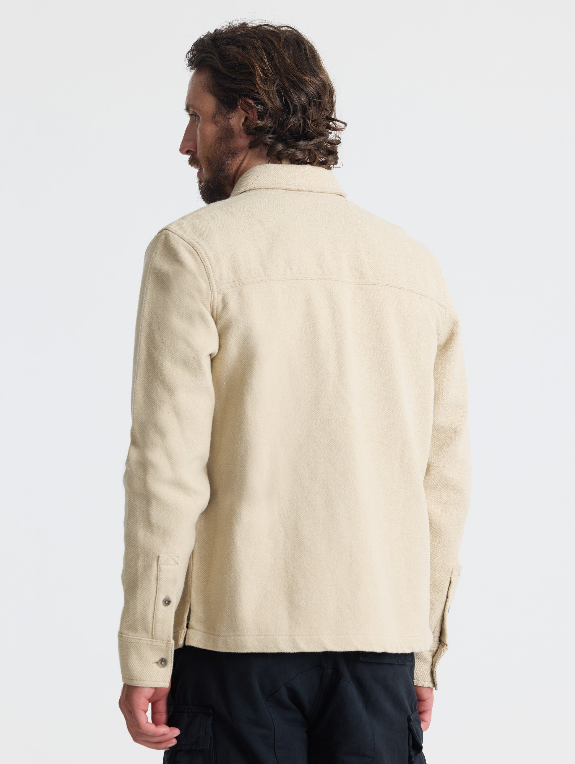 Rear, angled upper-body view of man wearing Pioneer Heavyweight Button-Down in Bone white from AETHER Apparel.