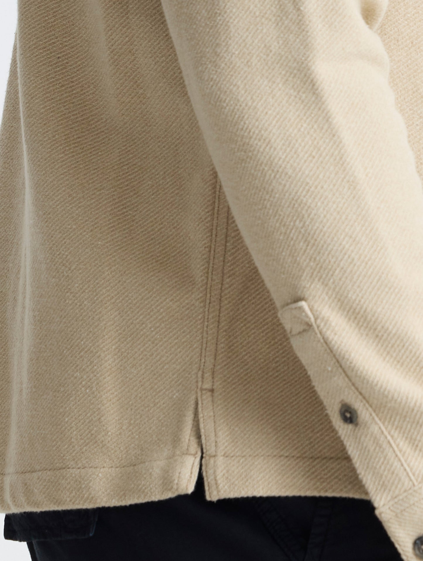Closeup detailed view of the on-seam side slits and split cuffs on the Pioneer Heavyweight Button-Down in Bone white from AETHER Apparel.