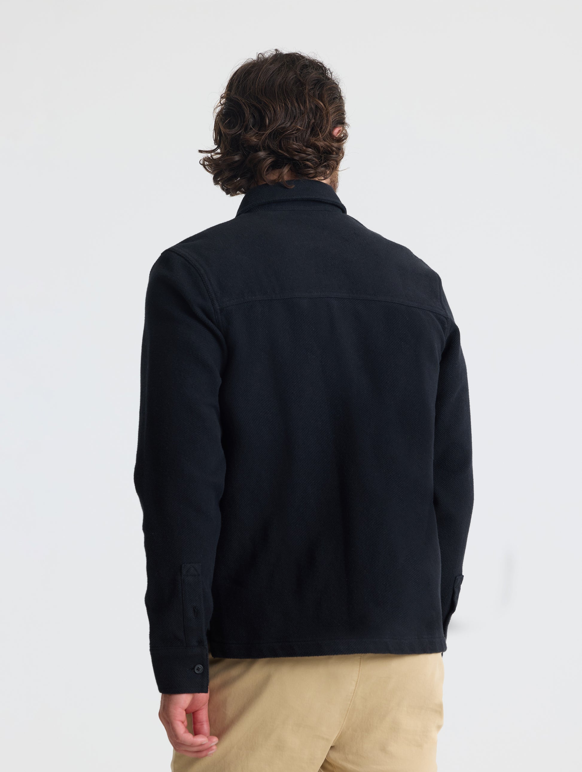 Rear, angled upper-body view of man wearing Pioneer Heavyweight Button-Down in Onyx Black from AETHER Apparel.