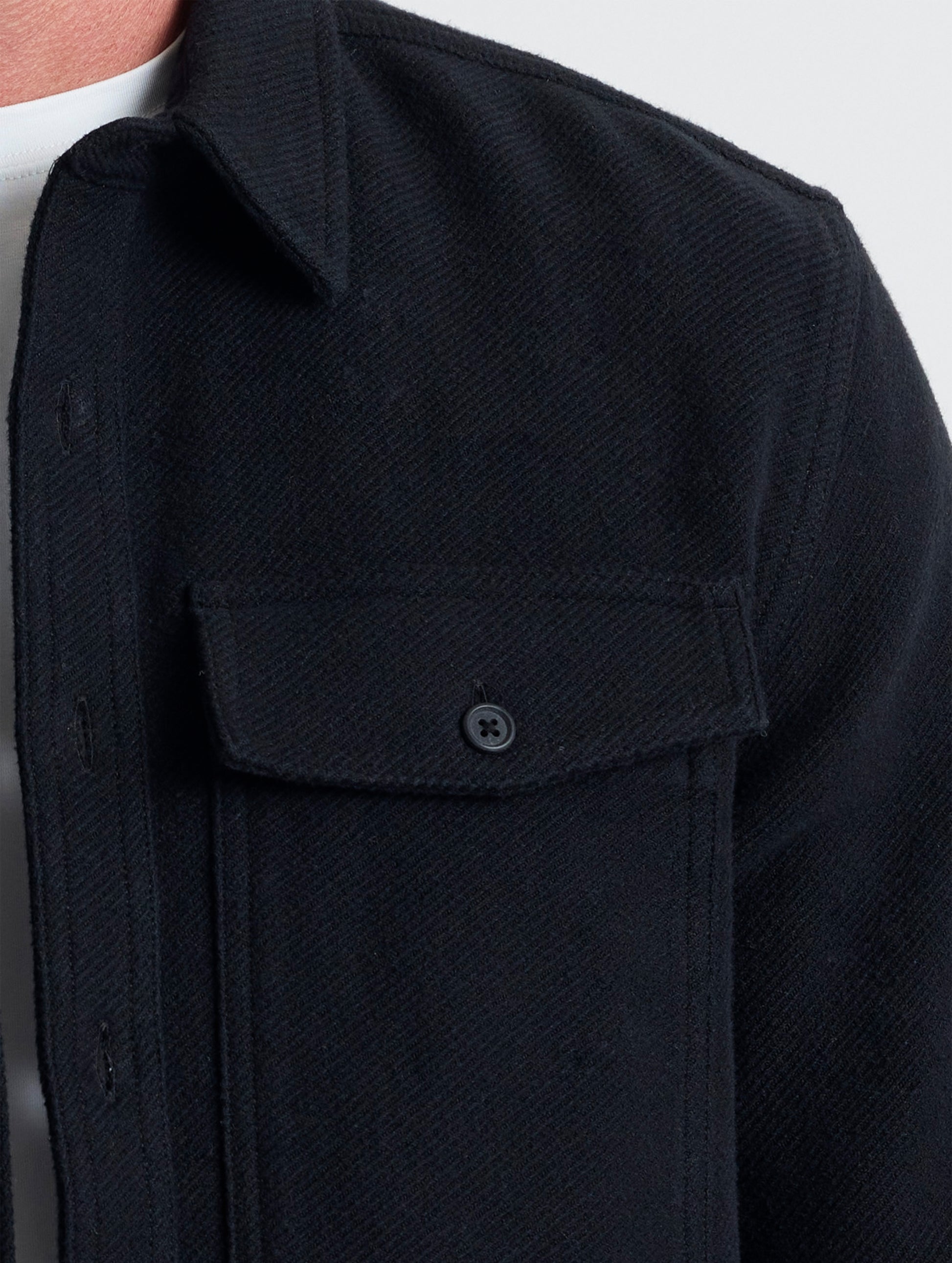 Closeup detailed view of the button-secured chest patch pockets on the Pioneer Heavyweight Button-Down in Onyx Black from AETHER Apparel.
