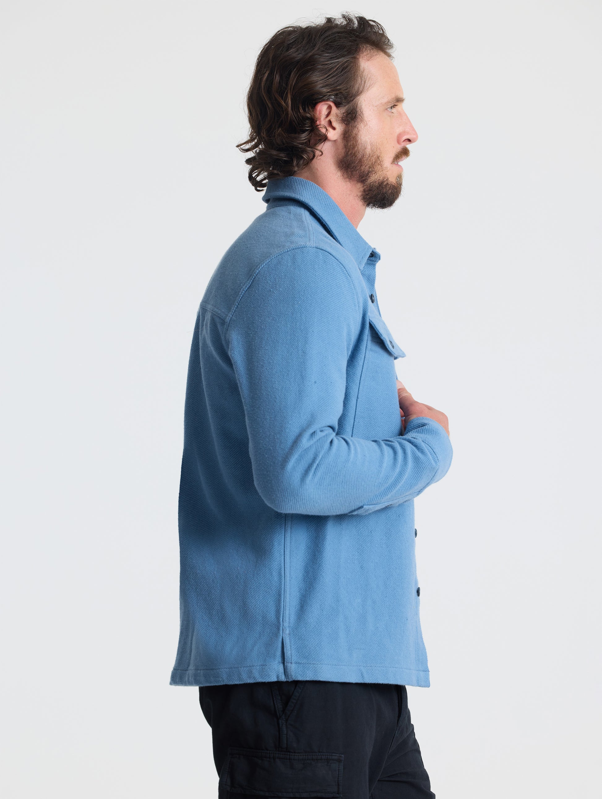 Side profile upper-body view of man wearing Pioneer Heavyweight Button-Down in Portal Blue from AETHER Apparel.